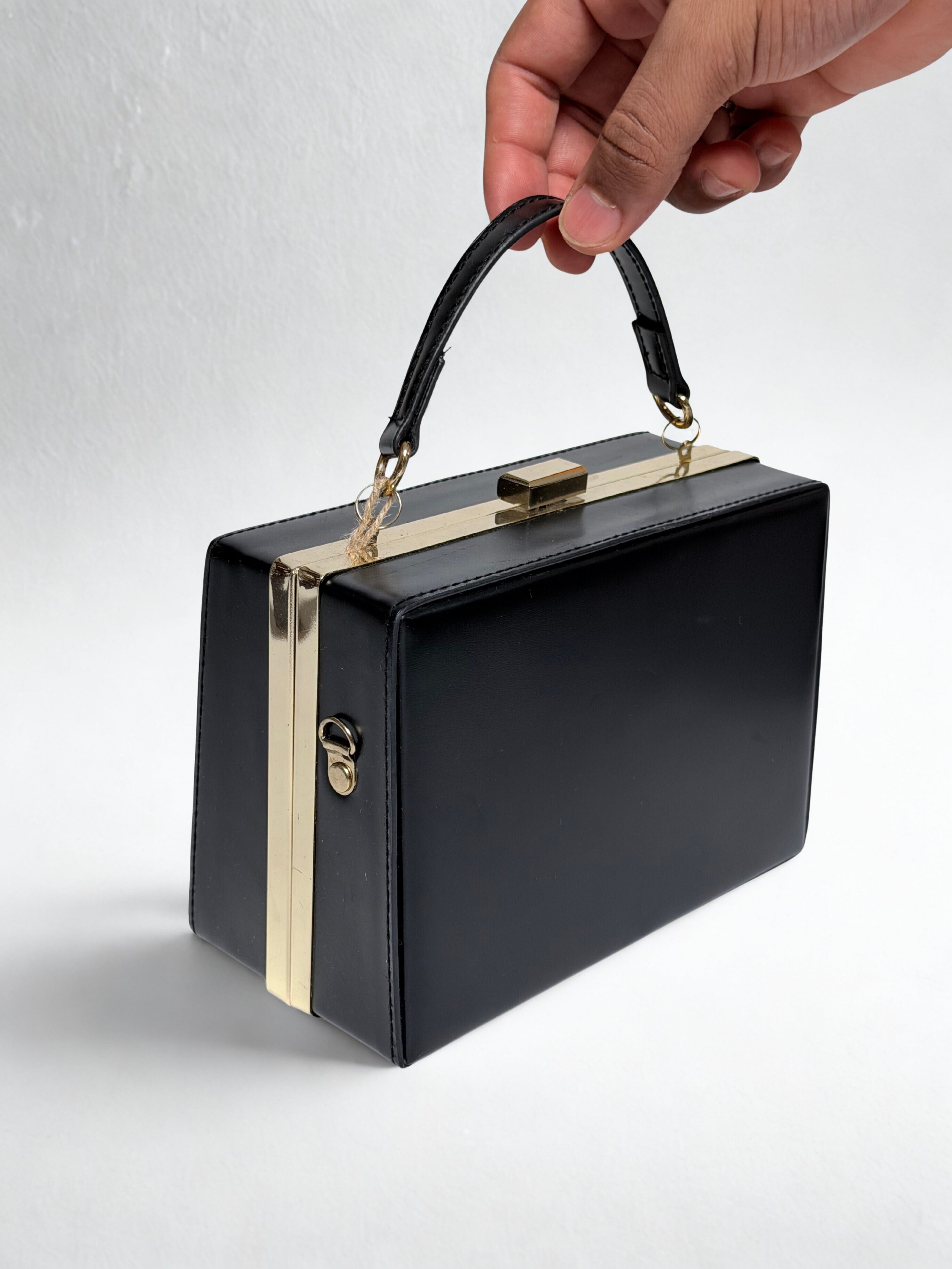 Handheld black bag with gold clasp being held
