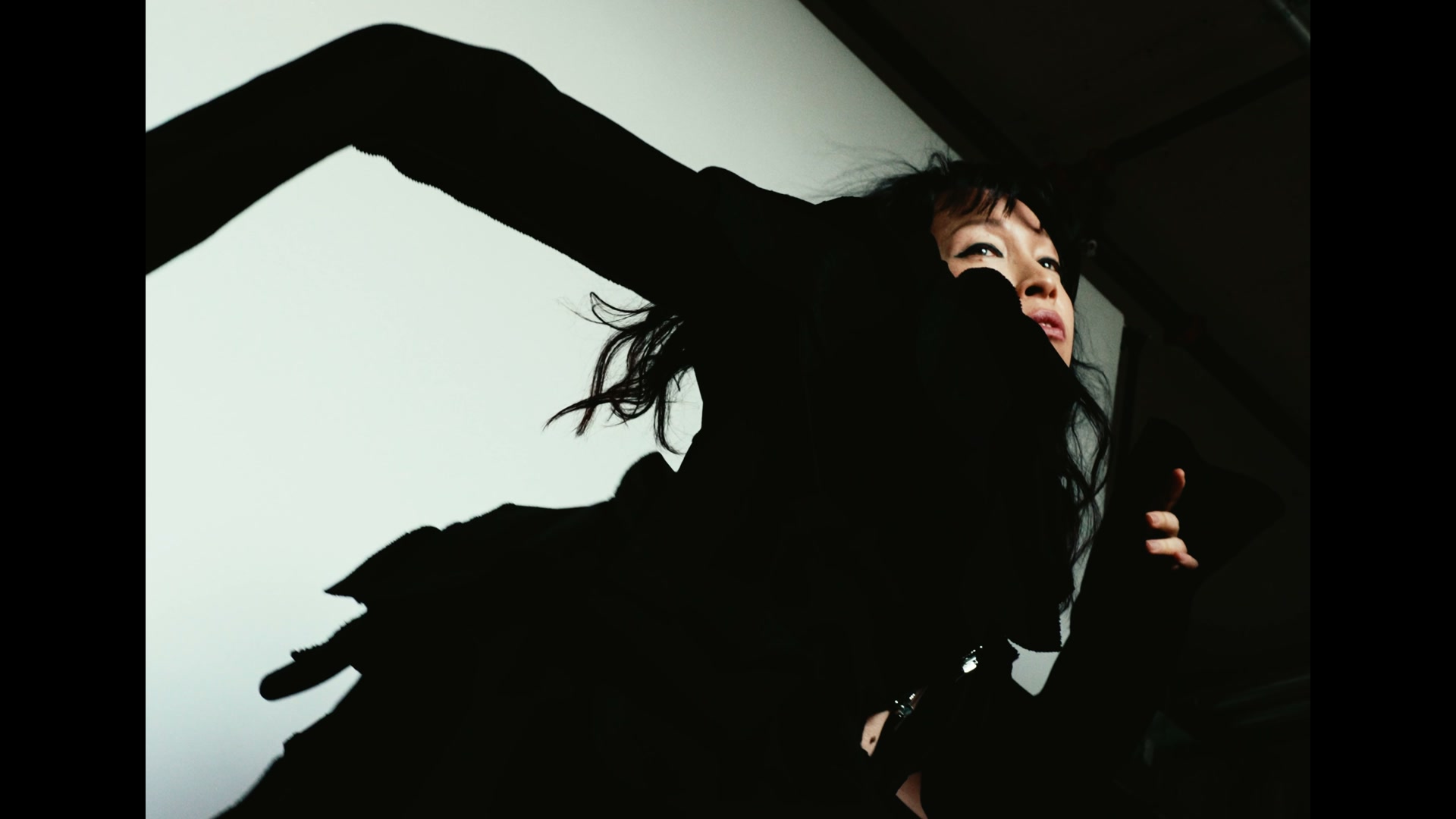 Still from NOAGENCY’s fashion film for The Forumist: silhouette with a raised arm against the lit backdrop