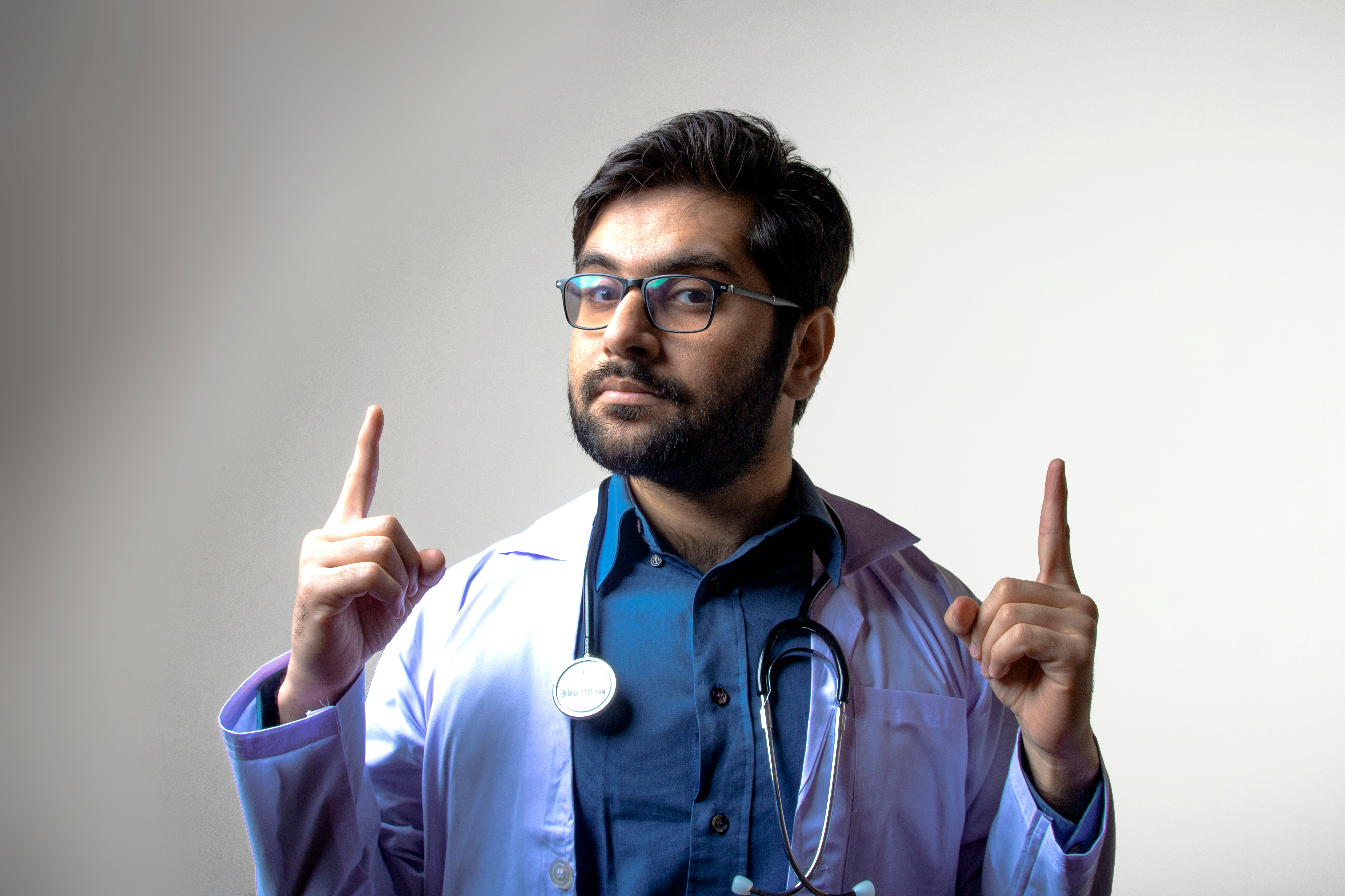 man in blue scrub shirt wearing black framed eyeglasses