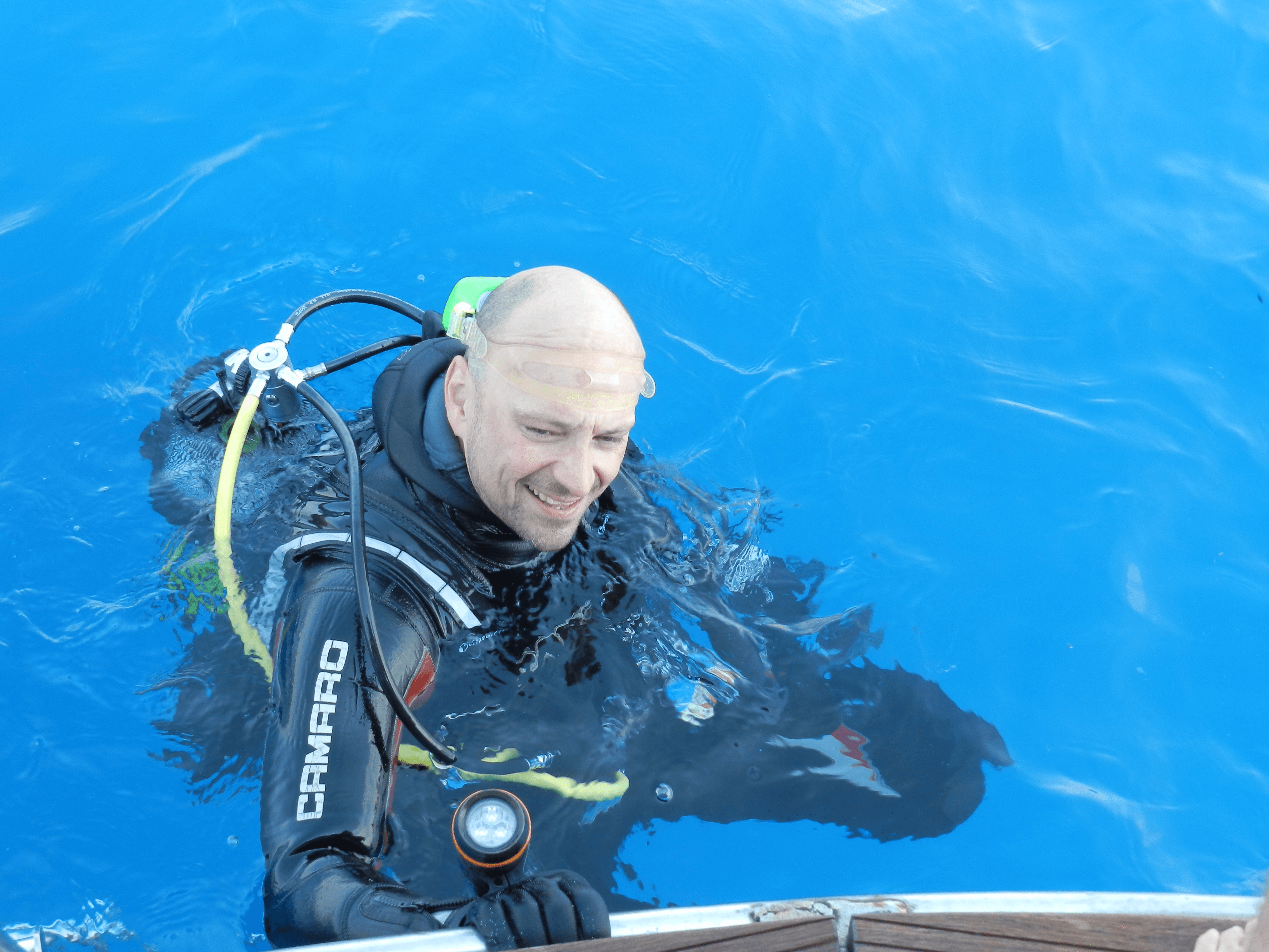 a woman scubas in the ocean with a camera