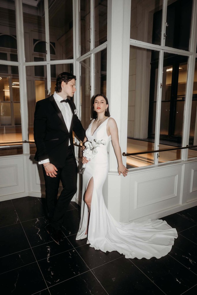 Brautpaar steht lässig in einem Wiener Hotel.