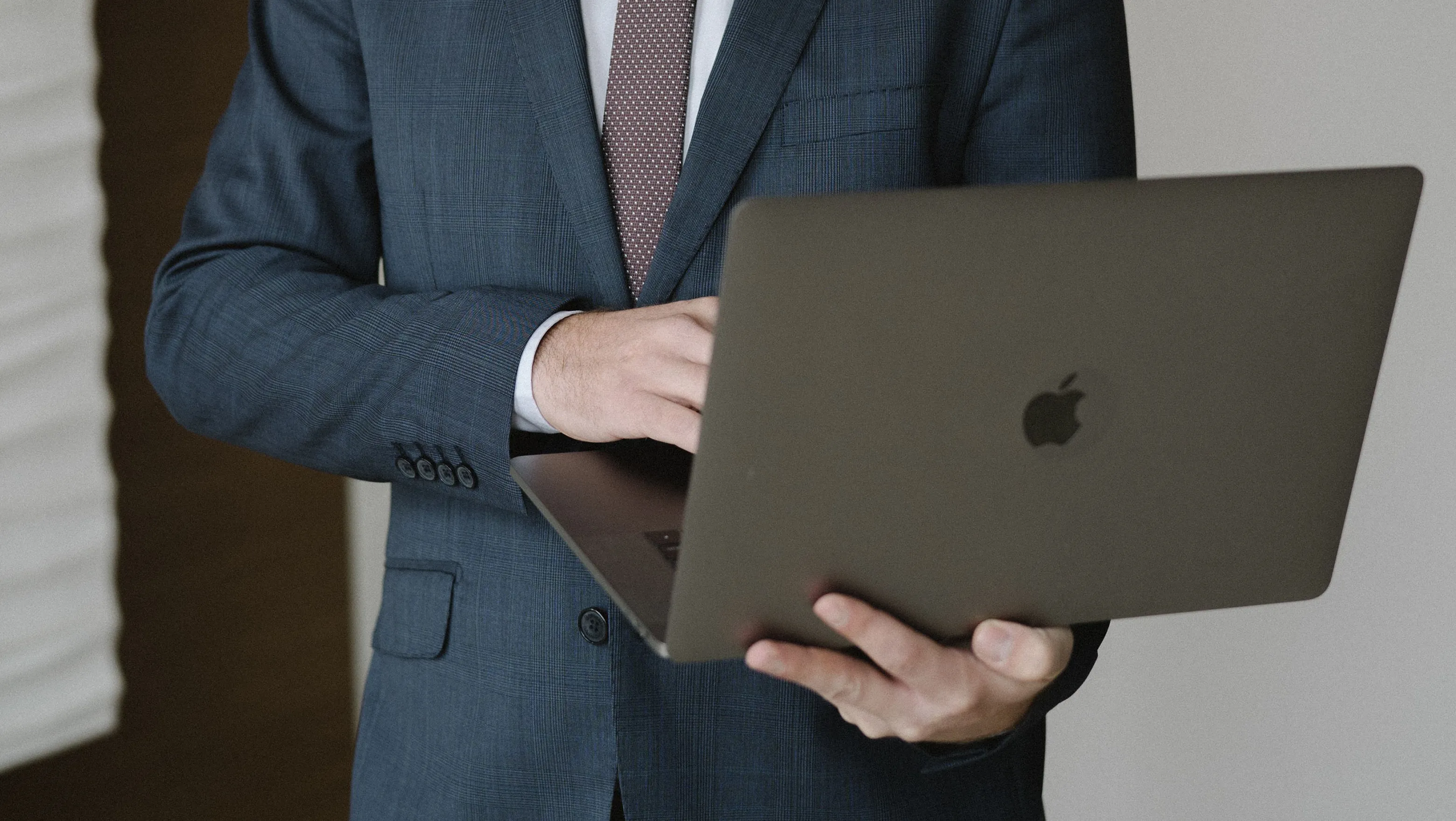 Hombre con traje usando su laptop de pie.