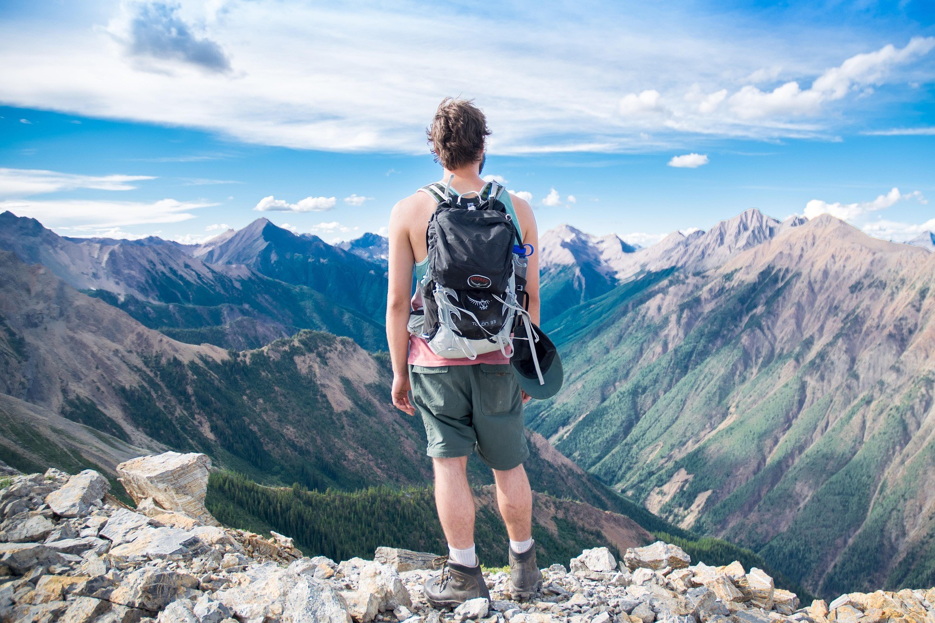 Hiker overlooking the Colorado Rocky Mountains on a sunny day, symbolizing a scenic summer getaway from Denver.