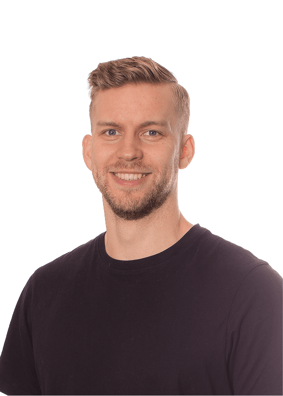 Person wearing a blue puffer jacket and red backpack standing in front of a light blue building on a city street.