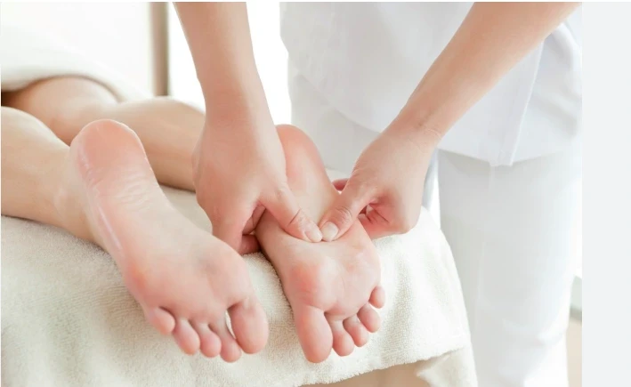 Close-up of a therapist performing a relaxing foot massage on a client lying on a spa bed, creating a soothing and rejuvenating experience.