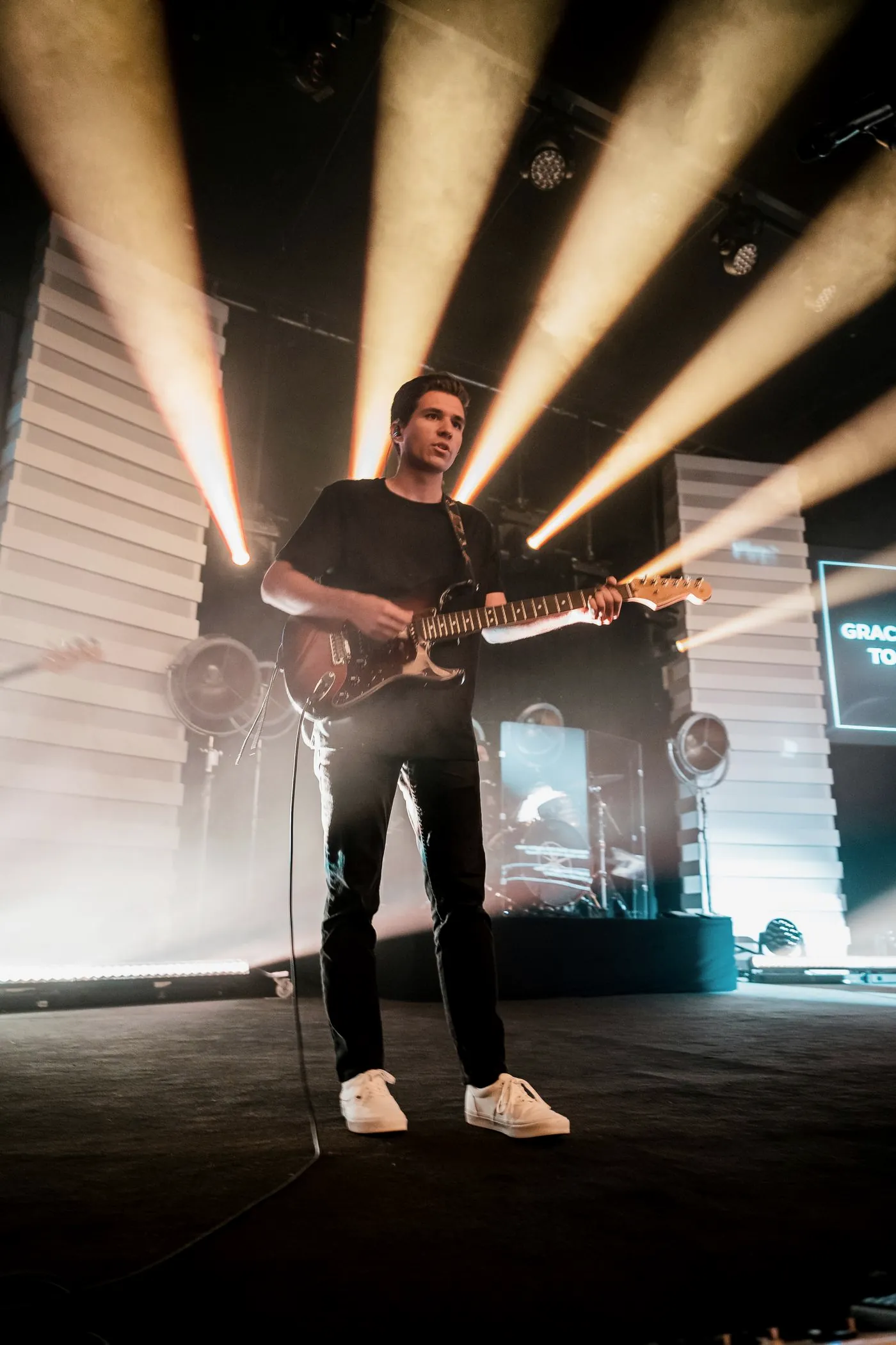 A guitarist on stage in front of beams of light
