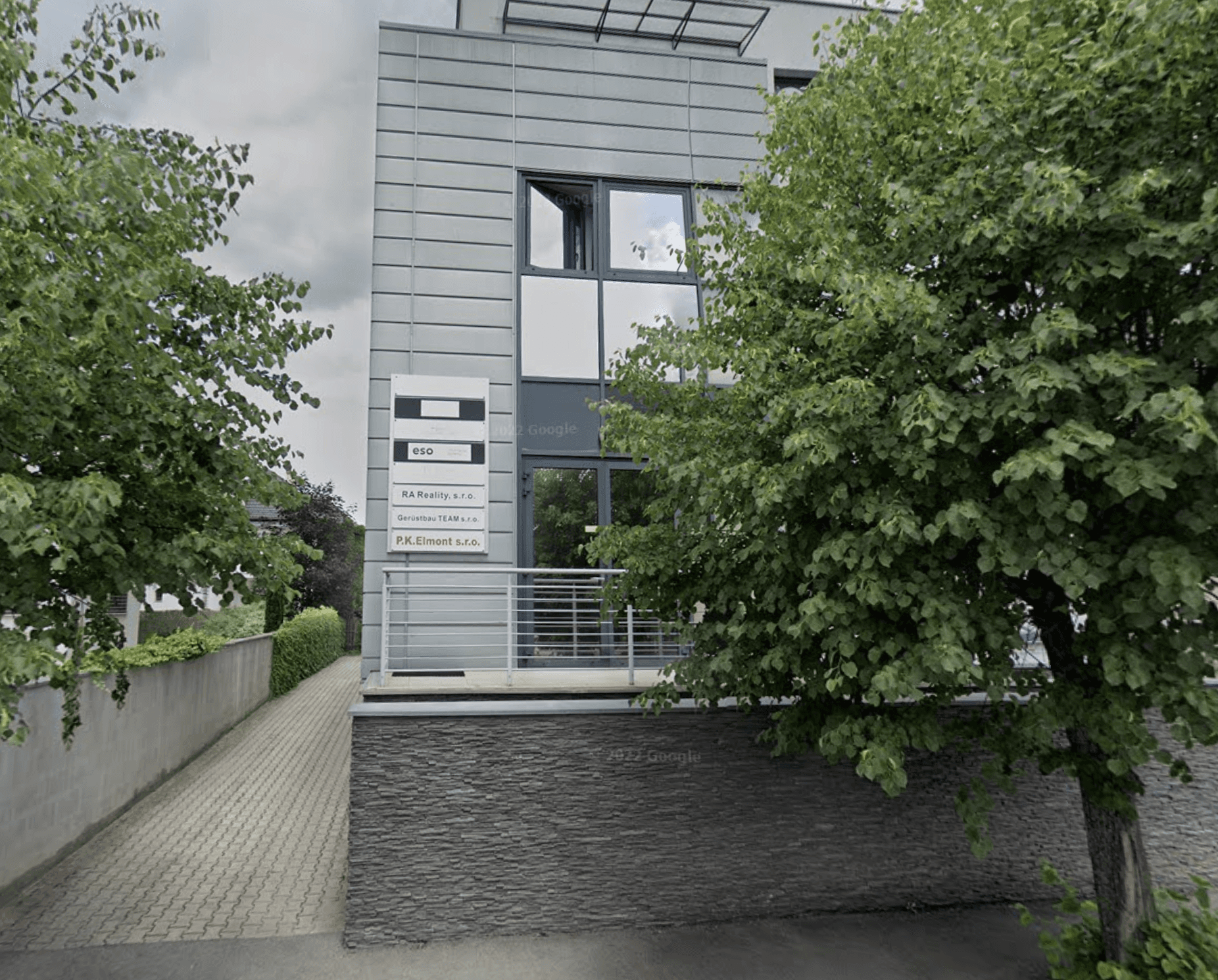 Modern luxury house on a hillside surrounded by trees, featuring large glass windows, a terrace, and a small pool at sunset.