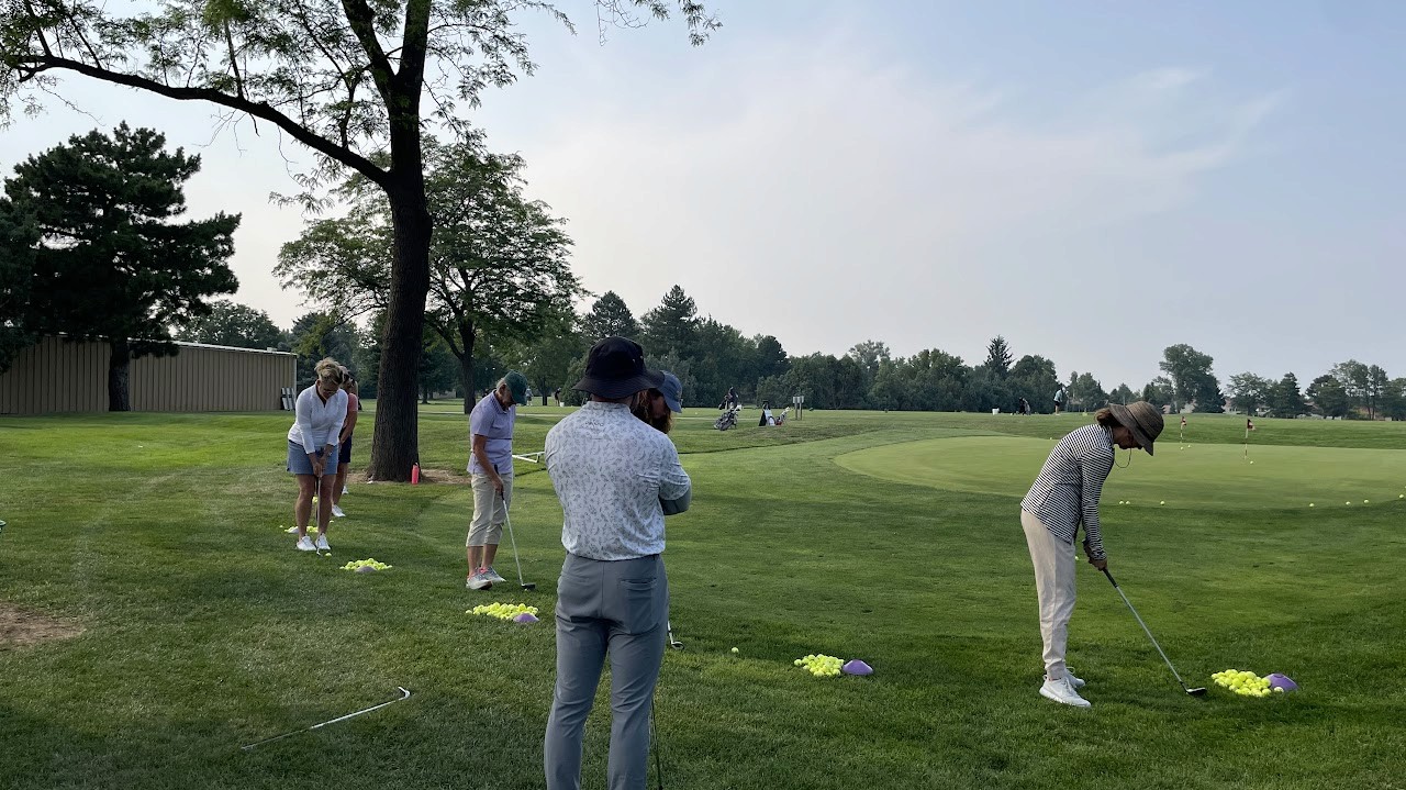 Students gathered on the edge of a green, practicing chipping.