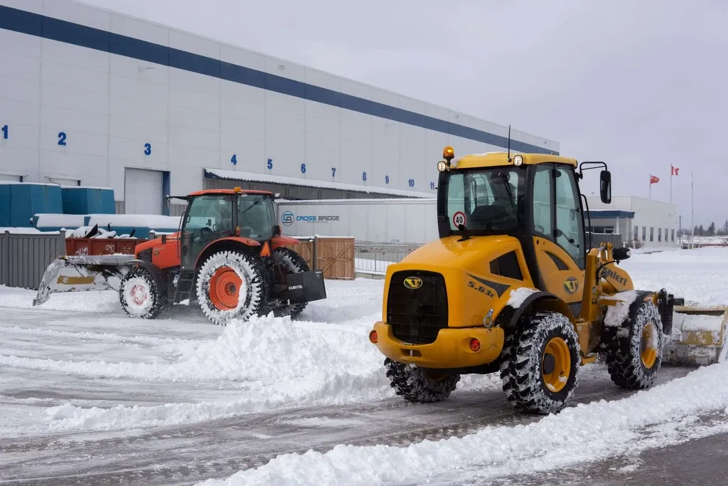 Falcons Landscaping operating heavy snowplow equipment at an industrial facility