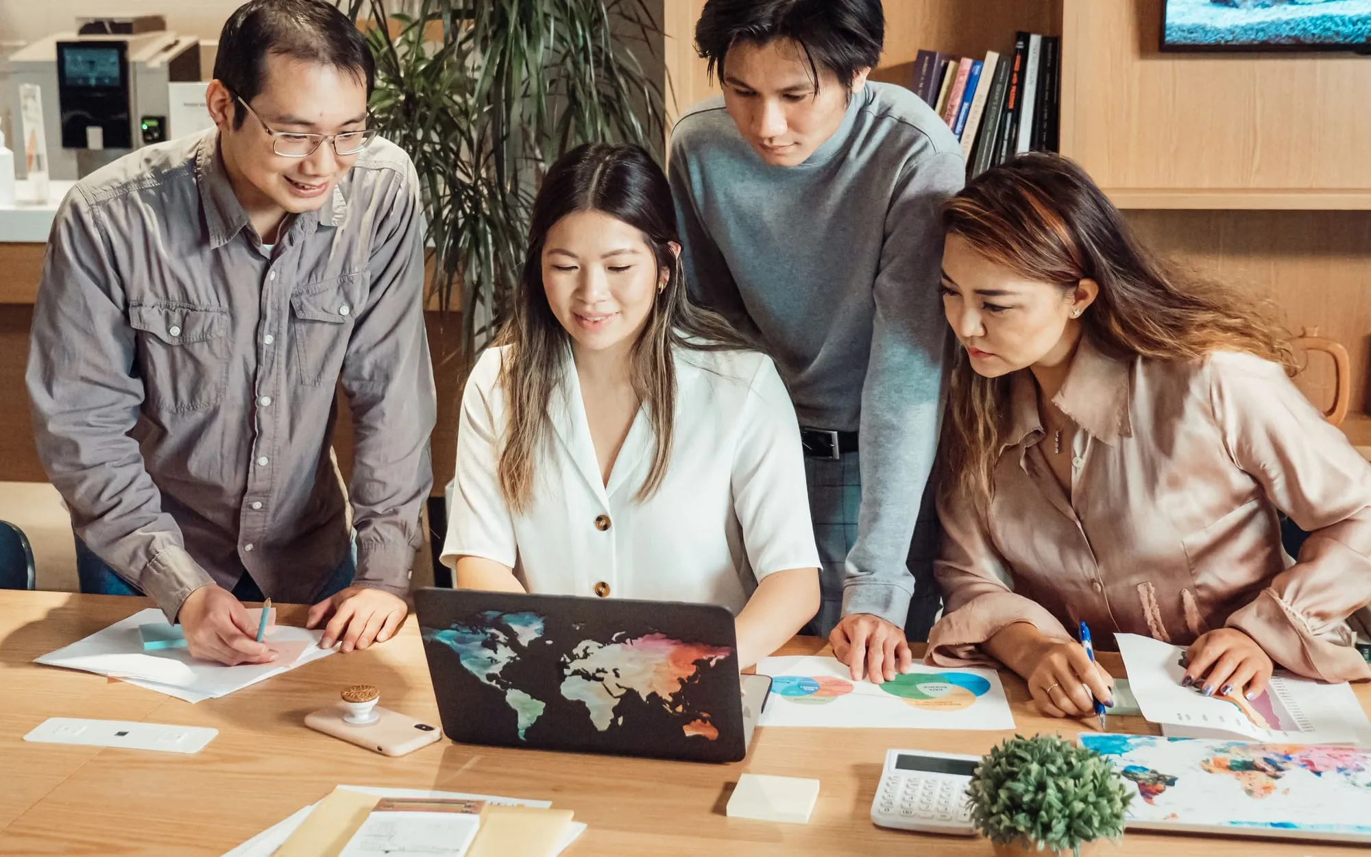 A team gathered around a table of laptops, discussing their work