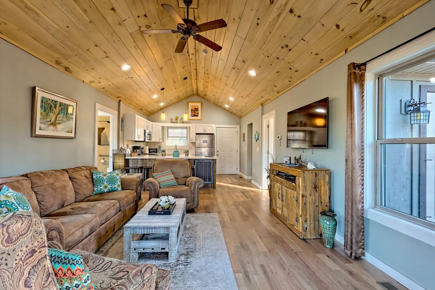 Eagles Nest great room with leather sofas, a vaulted pine ceiling and the kitchen beyond