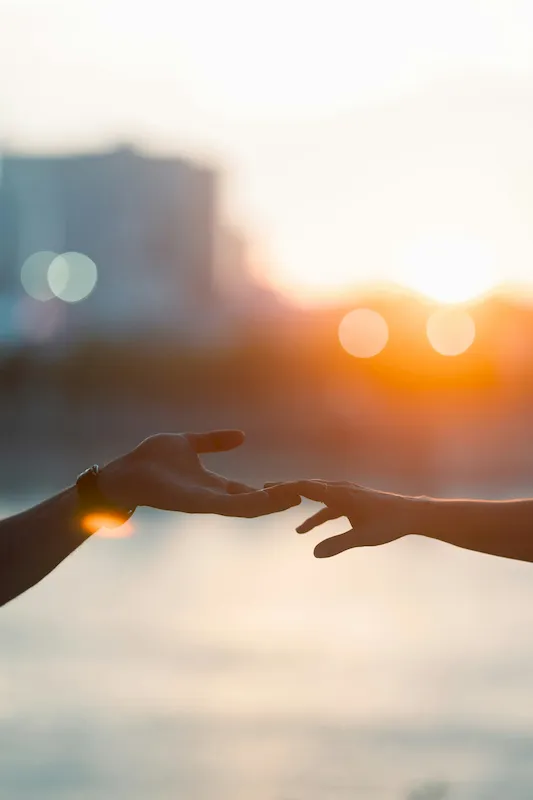 Two people reaching out and touching hands