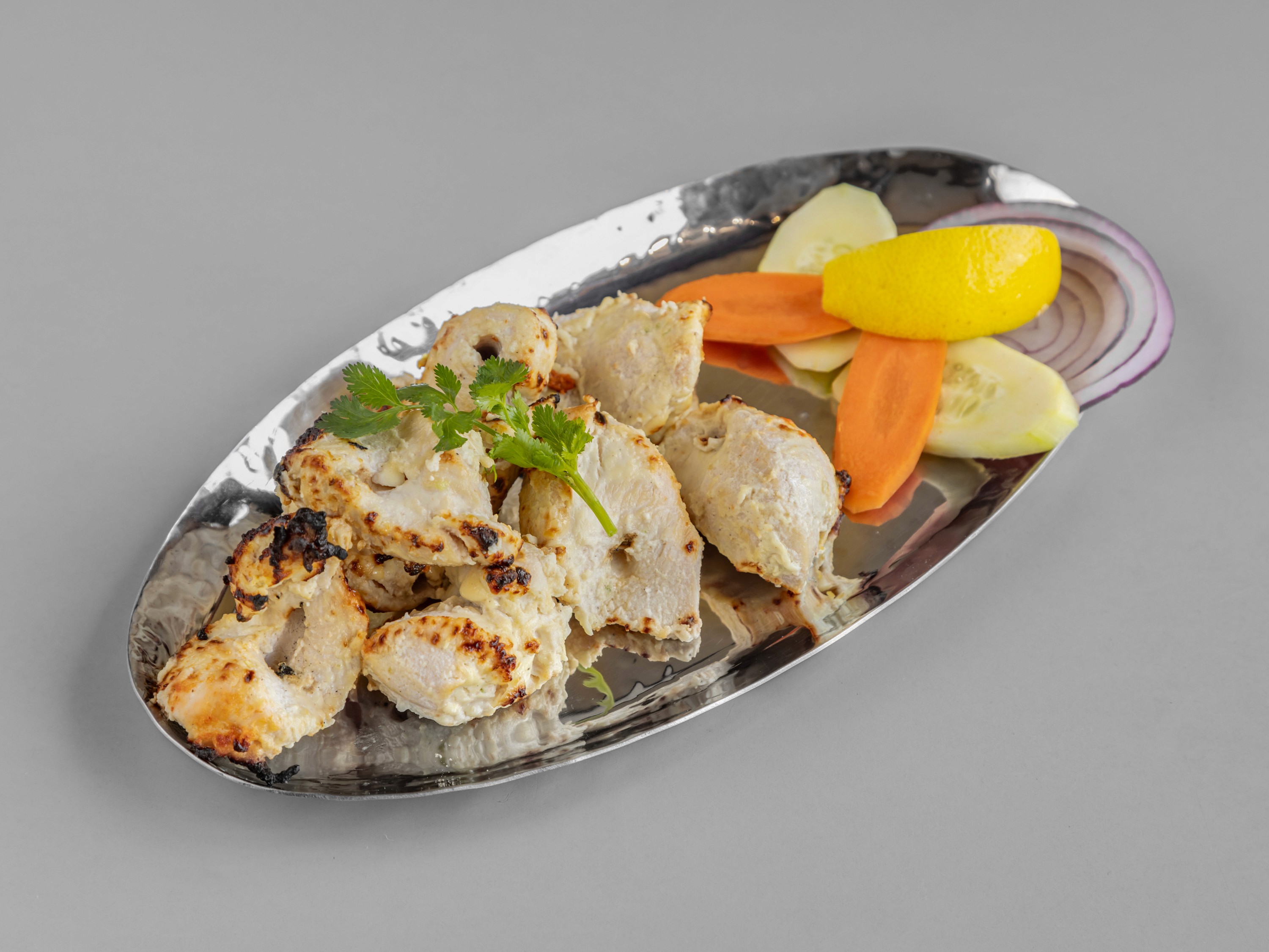 A rustic indoor scene featuring a table set for a meal, including two bowls of rice-based dishes topped with garnishes, an oil bottle, bread, a glass of juice, and milk bottles, all bathed in natural light streaming from a window.