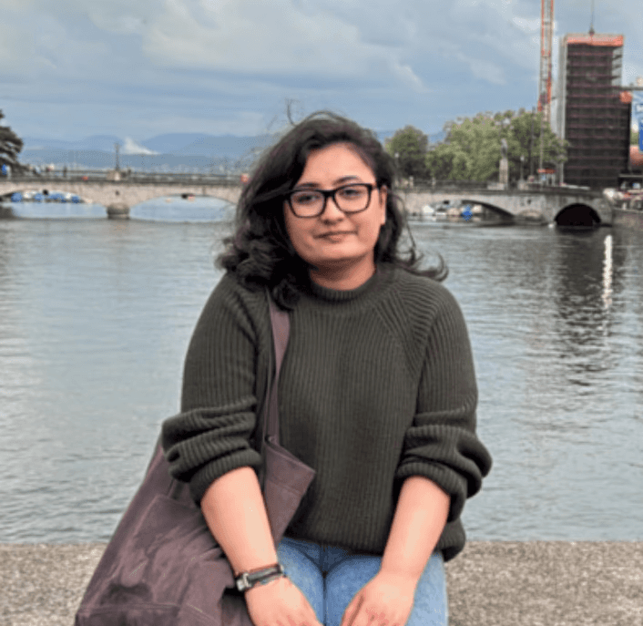 A thoughtful young person with dark hair gazes to the side, captured in soft black and white lighting.