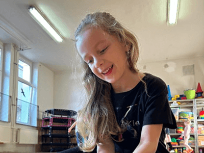 Portrét usměvavé holčičky s dlouhými vlasy ve třídě