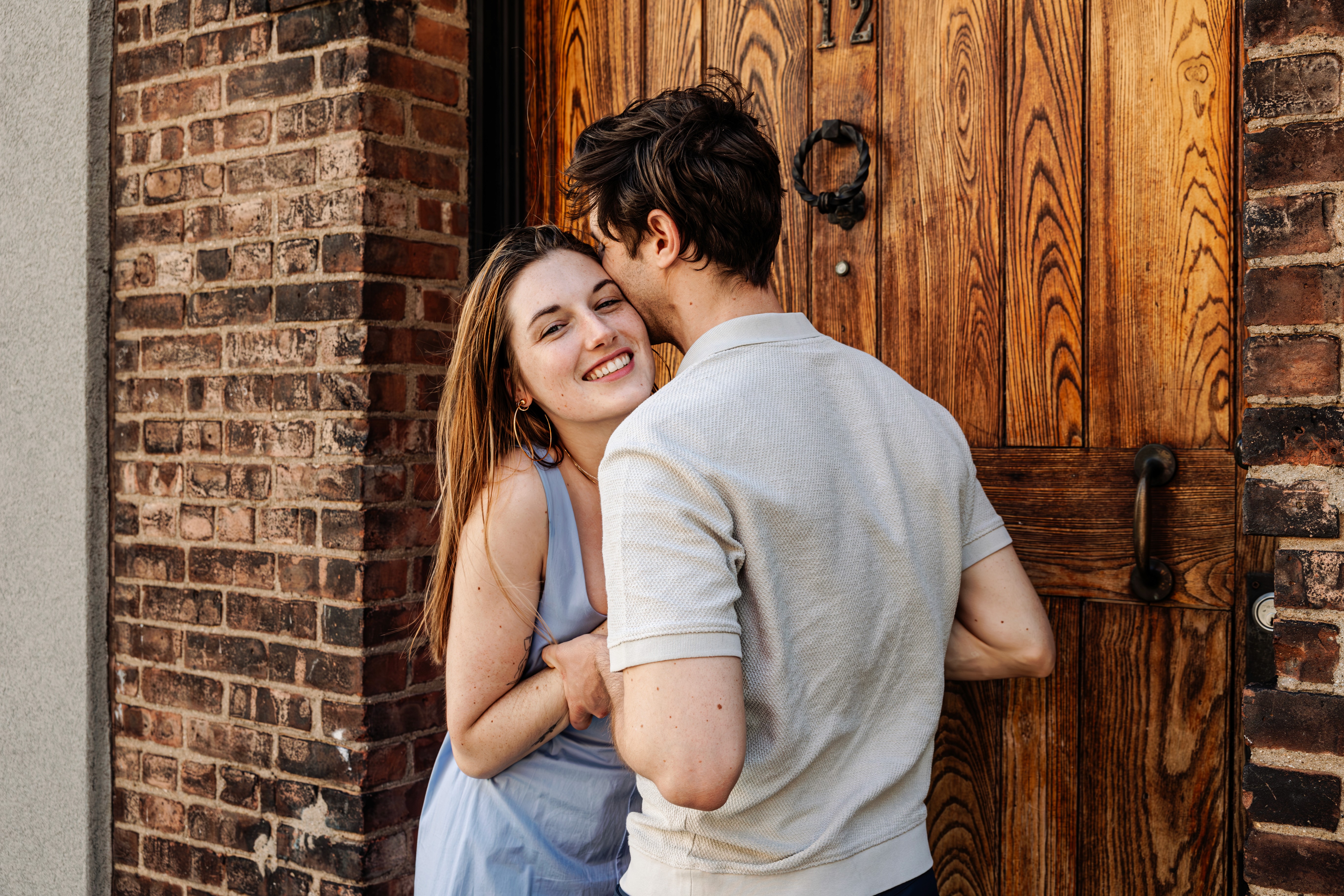 5:10 PMShe's beaming at the camera, arms wrapped around him, his face tucked away — an intimate, close-up couples portrait at the cobblestoned Washington Mews in Greenwich Village, NYC by Lizz Spano Photography, New York City couples photographer.