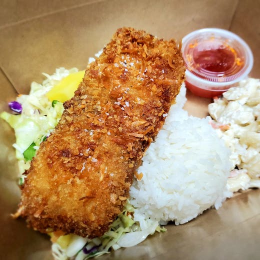 A large, golden-brown coconut-crusted Mahi Mahi filet served with two scoops of rice, macaroni salad, and a side of red Thai sweet chili sauce.