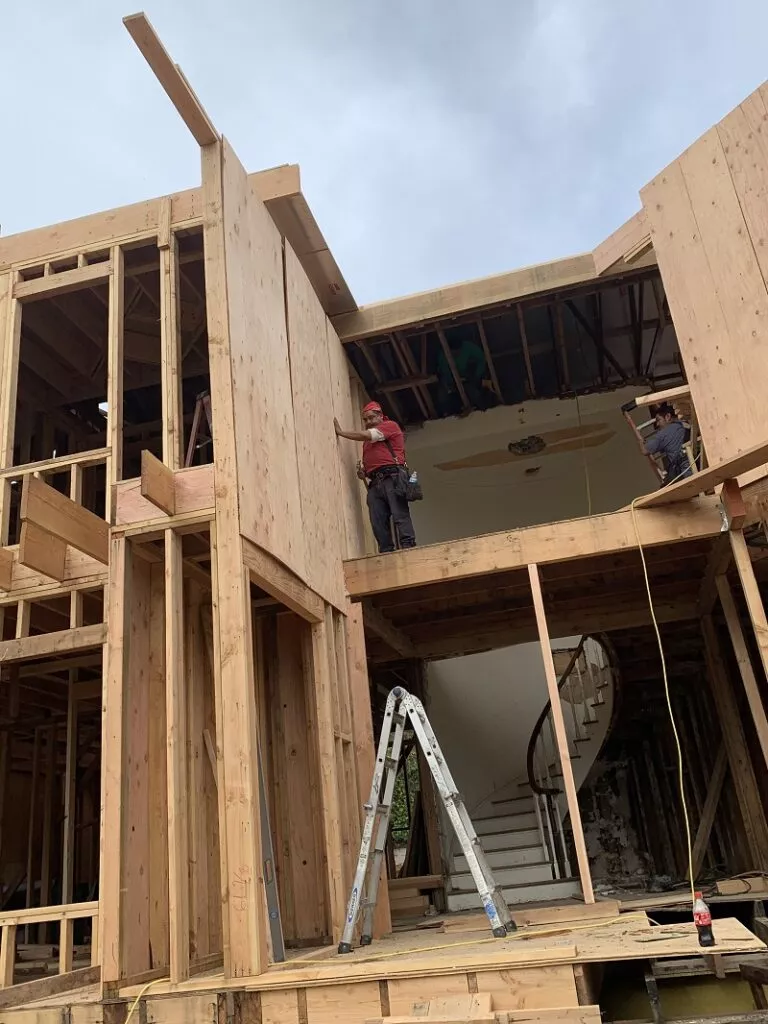 Residential wood framing under construction with workers preparing the structure for a framing inspection.