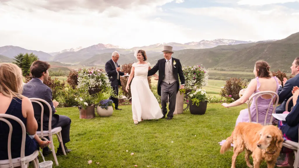 The bride and groom walking down the aisle together after their ceremony, smiling at guests during a Chaparral Ranch Wedding