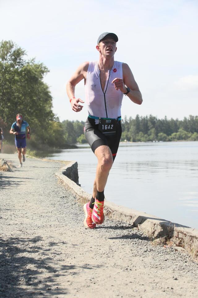 Triathlete wearing white tri suit running along a river
