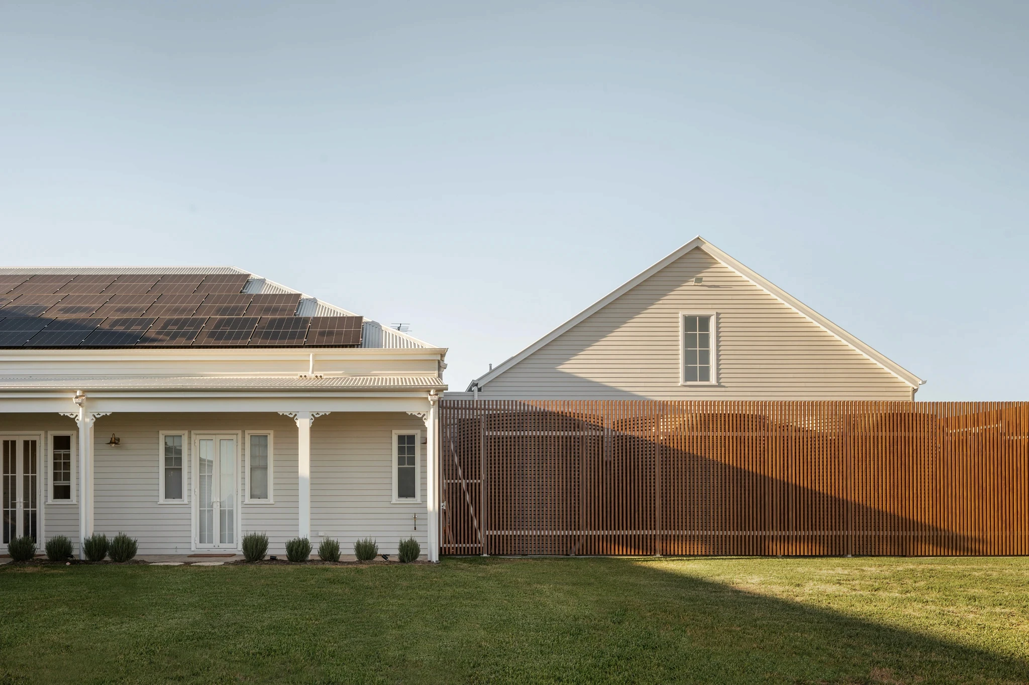Brisbane home featuring a large roof solar panel system and timber batten screening for sustainable, self-sufficient design.
