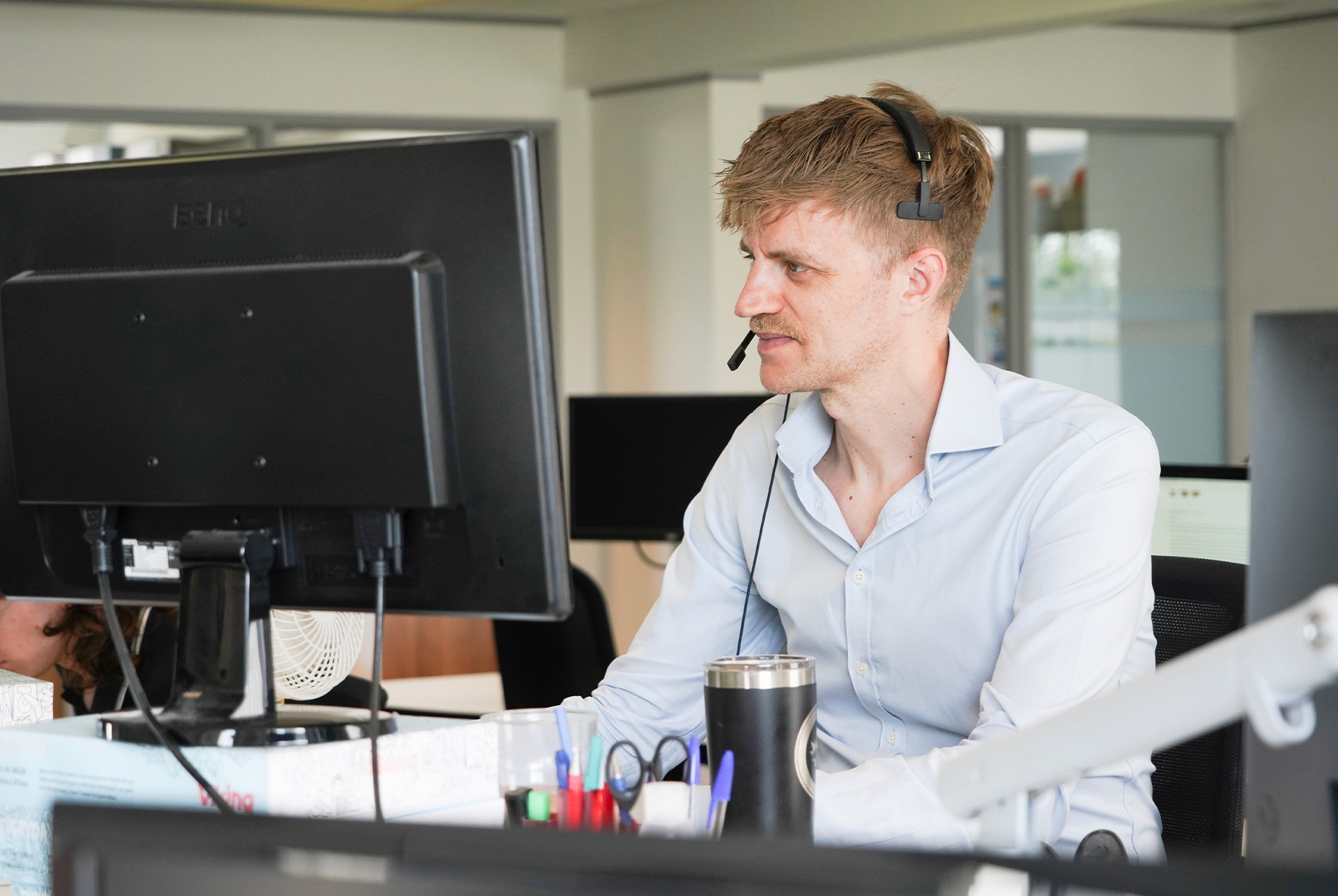 Hughes Price Walker support team member using a headset while assisting clients at a computer.