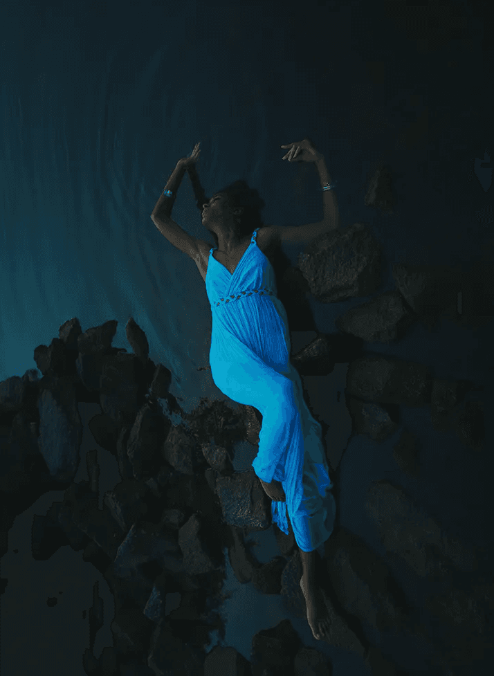 Black Woman wearing blue dress floating the water like an angel