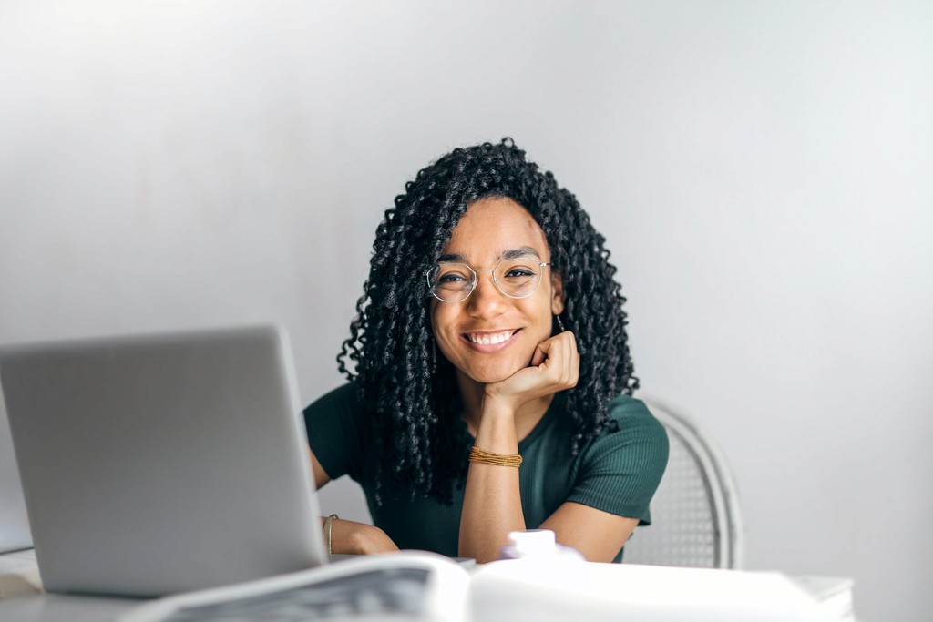 Smiling woman with glasses using laptop for online work.