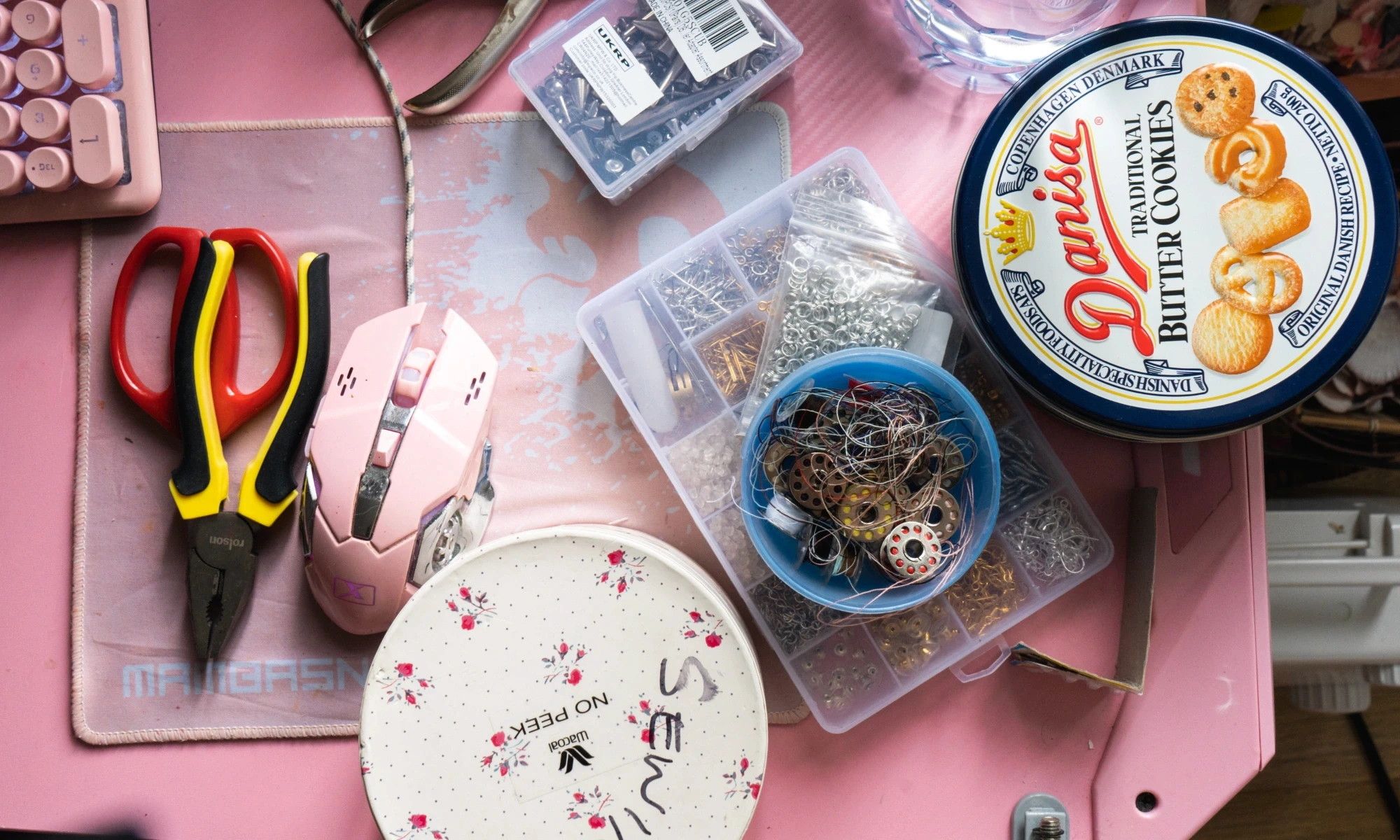 Top view of desk with mouse, sewing kit, biscuit tin