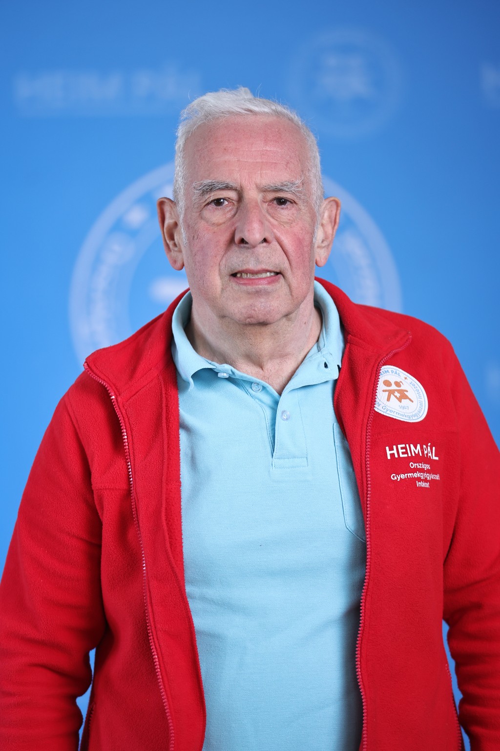 Ősz hajú férfi piros kardigánban