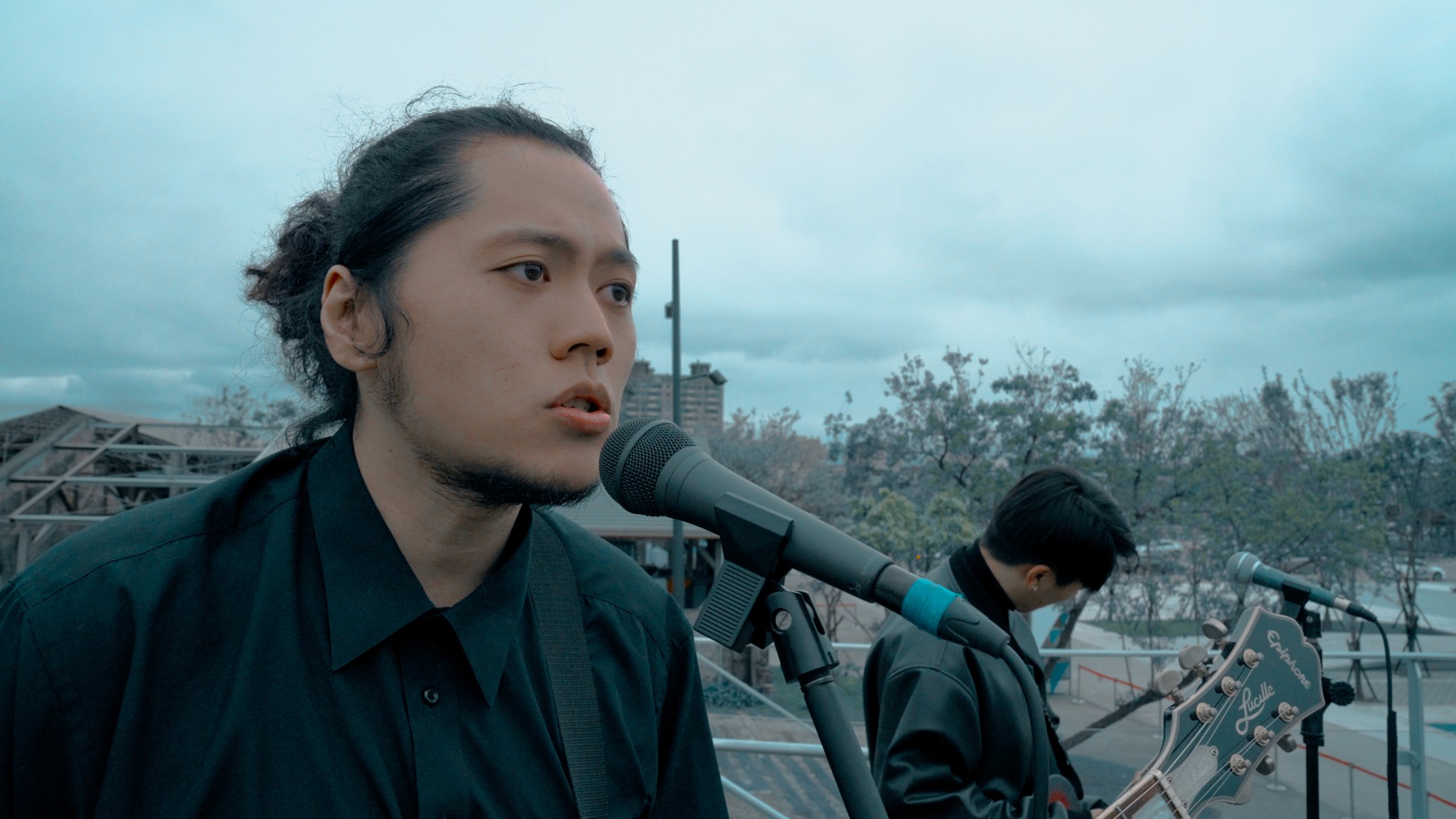 Two filmmakers operate a large camera in a dimly lit studio, wearing headphones and focused intently on the screen, conveying concentration.