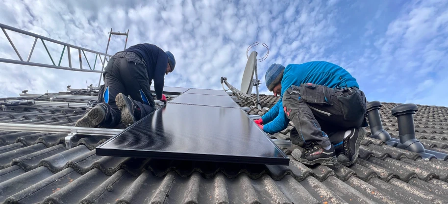 Zwei Solarteure installieren eine Photovoltaikanlage auf einem Dach