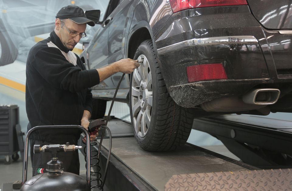 Un mécanicien contrôle la pression d’un pneu dans un atelier automobile.