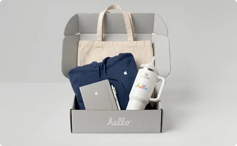 A swag kit containing a tote bag, a blue hoodie, a gray notebook, and a Stanley tumbler.