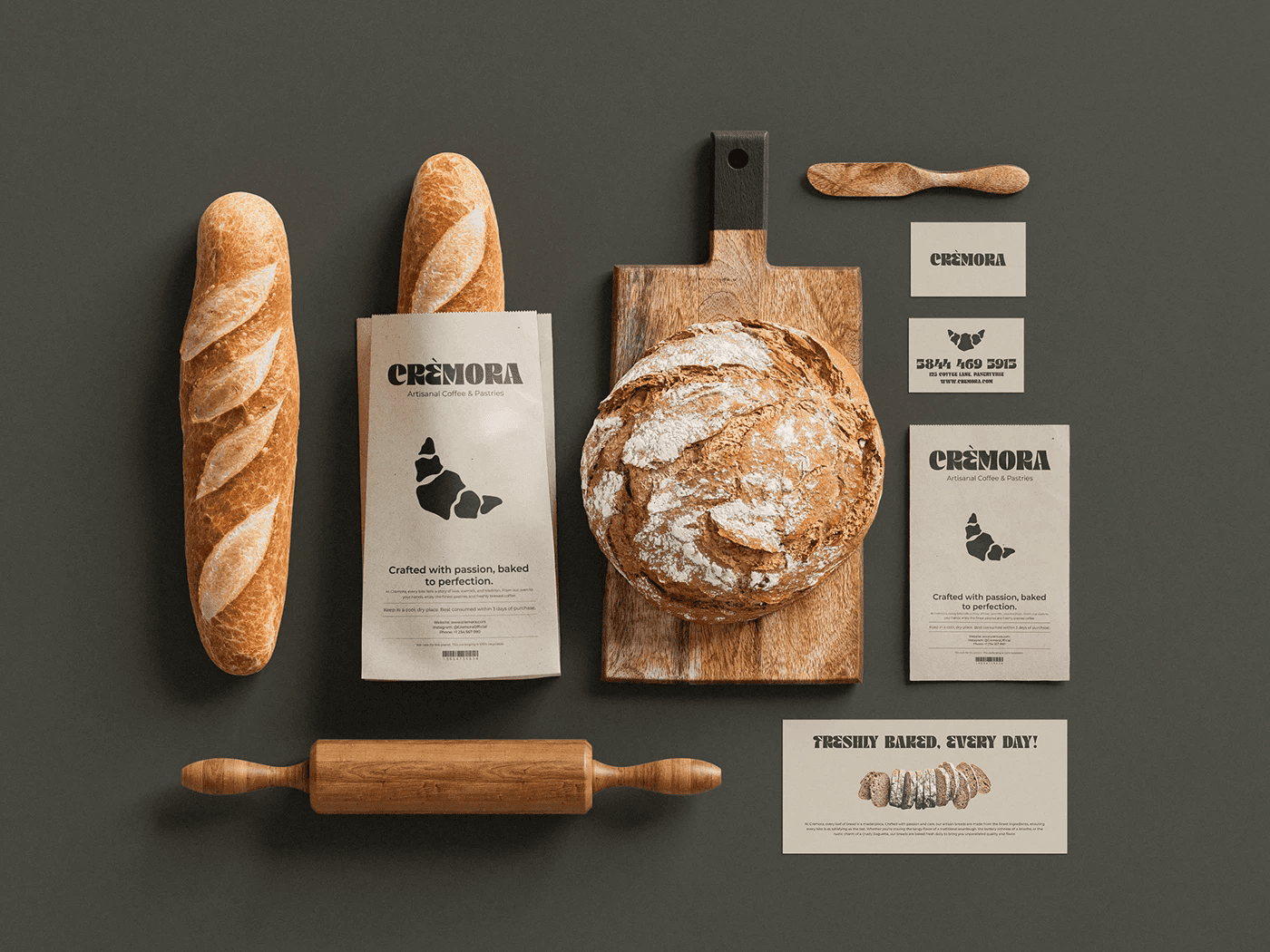 Crèmora bakery packaging flatlay featuring kraft paper bread bags, business cards and rustic bread on a wooden board, designed by Arteneldigitale.
