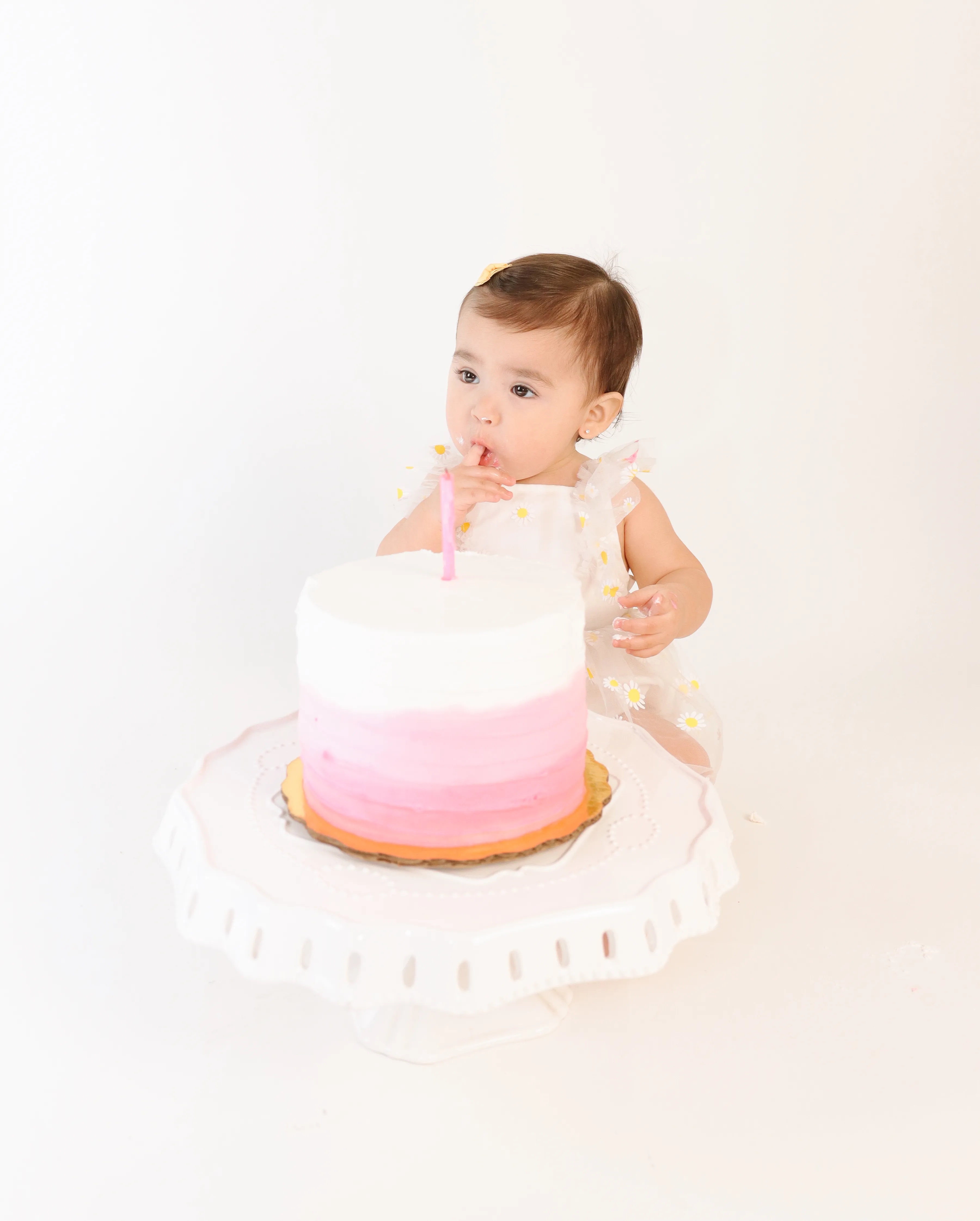 Bebé explorando un pastel blanco y rosa en sesión Smash The Cake