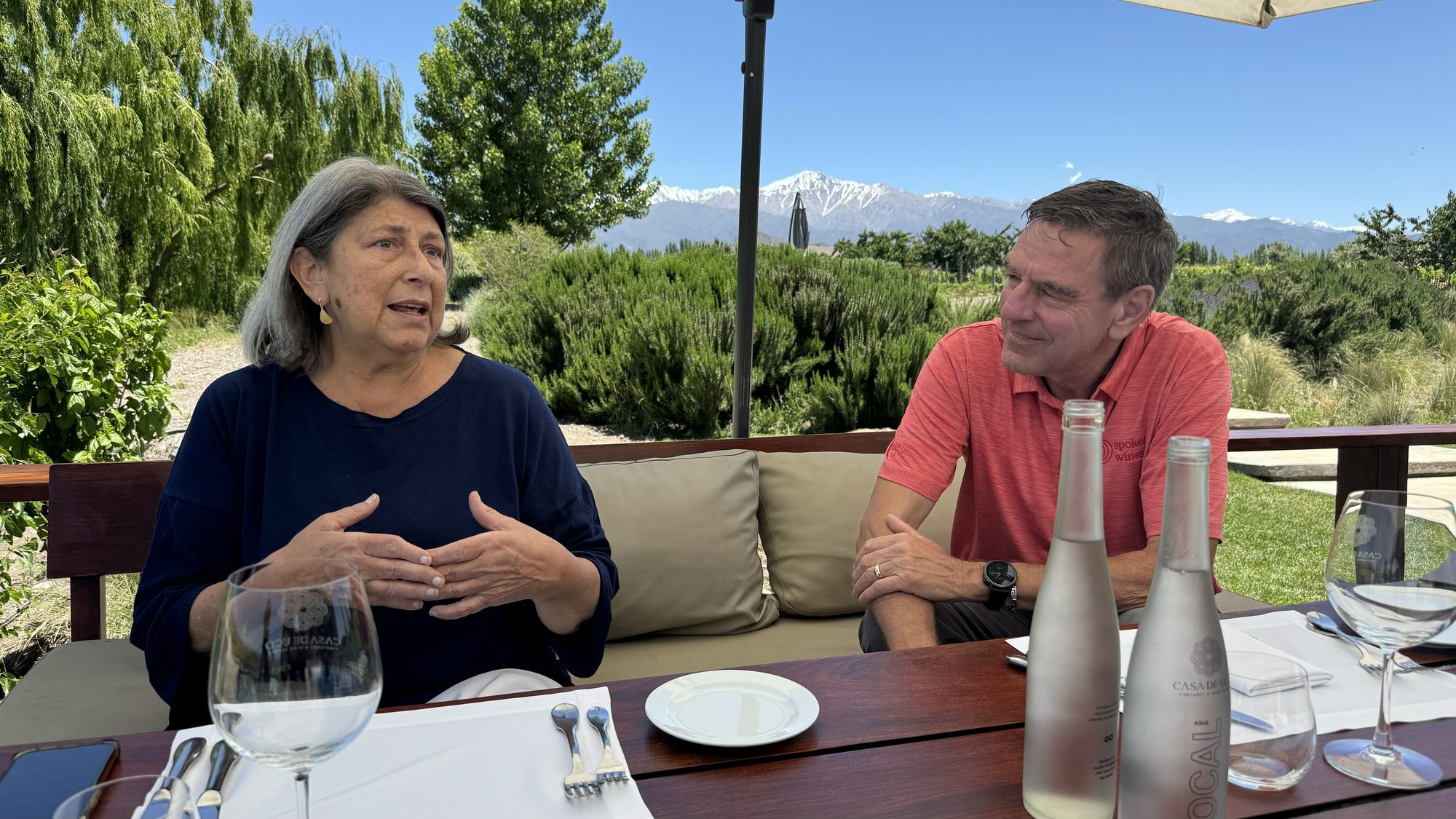 Adriana speaking with Jan de Weerd during an outdoor lunch at Casa de Uco winery in Mendoza’s Uco Valley, Argentina, with the Andes Mountains in the background.