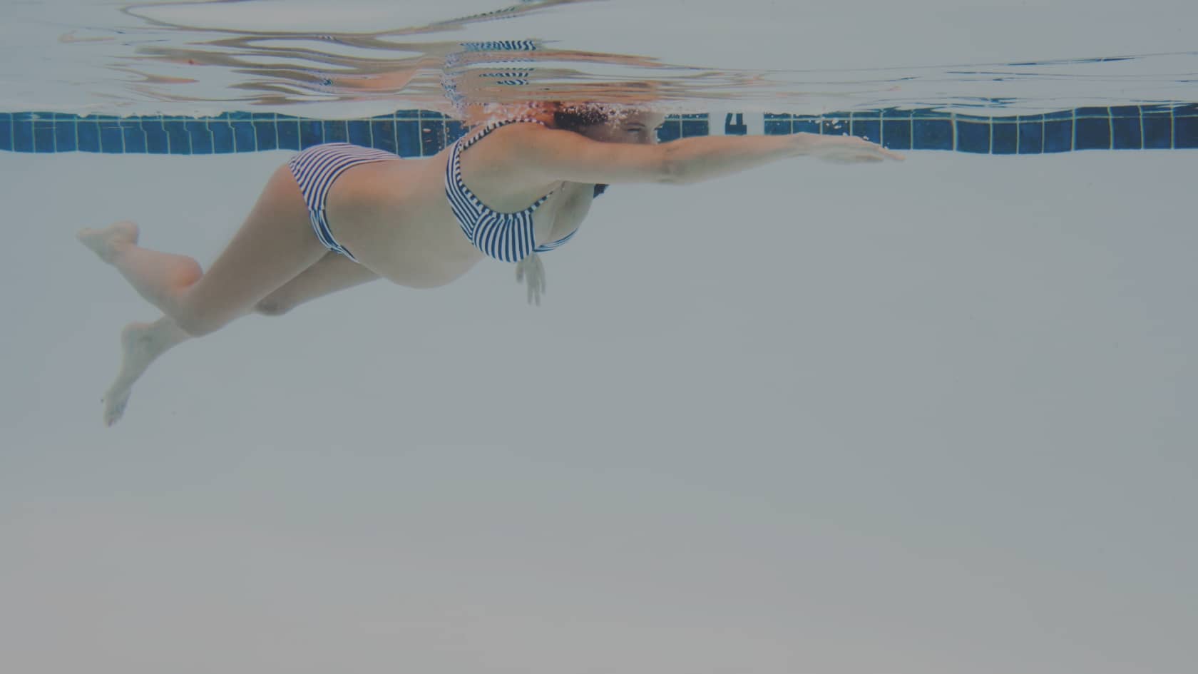 Femme enceinte en maillot de bain profitant des bienfaits de la piscine pendant sa grossesse.