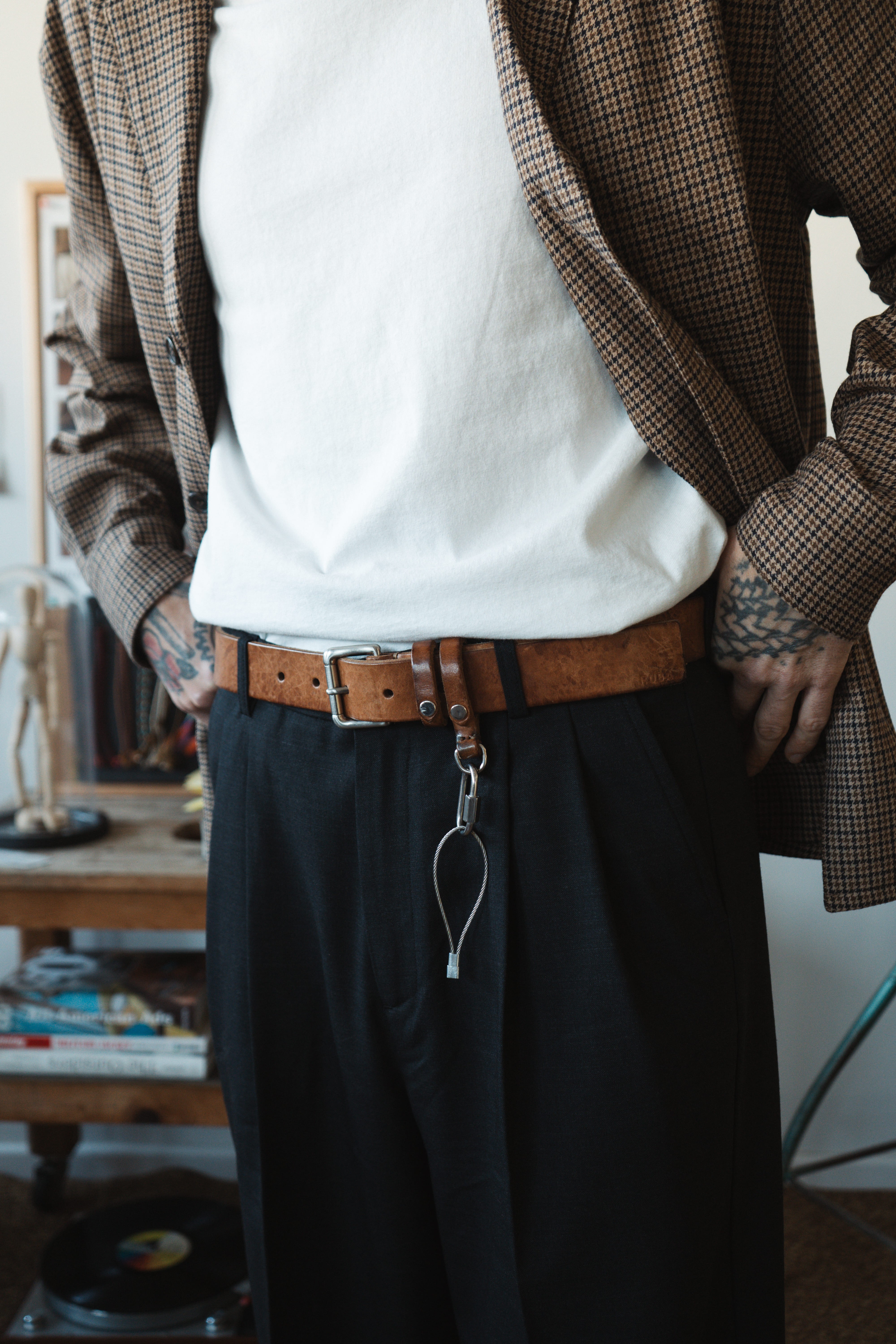 Détail de look masculin par Wooden Store avec une veste à carreau, un t-shirtblanc et un pantalon noir, le tout fabriqué en Italie