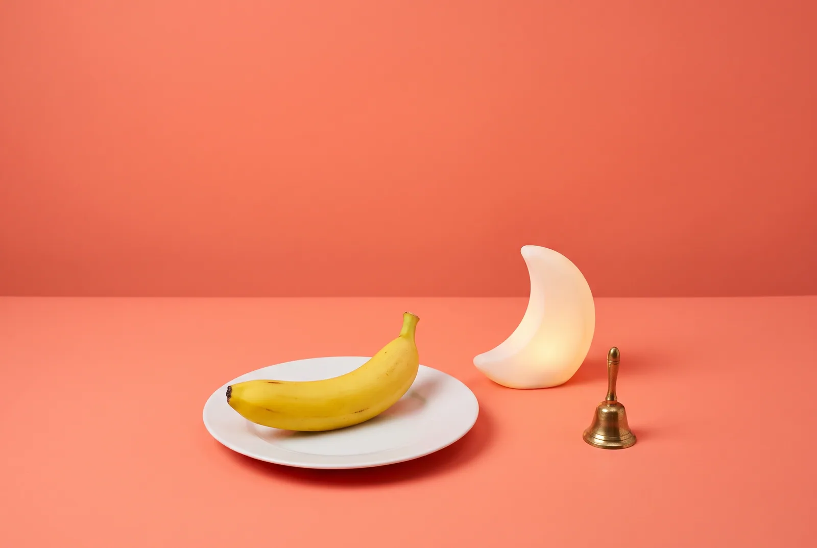 A banana beside a crescent moon night lamp and a small bell, late-night urge help in QUITTR vs Covenant Eyes
