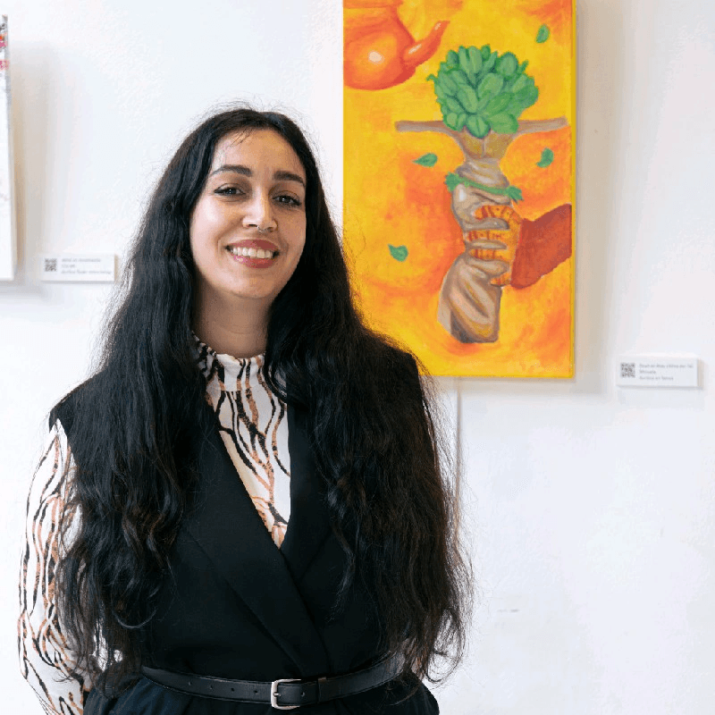 Donna sorridente, in piedi accanto a un dipinto astratto colorato in una galleria