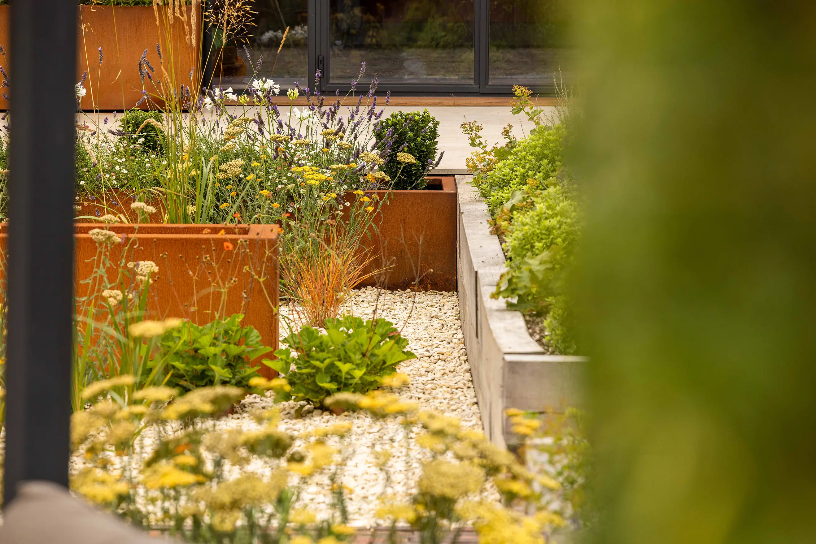 A garden featuring wooden planter boxes filled with various plants and greenery, set in a tranquil outdoor space.