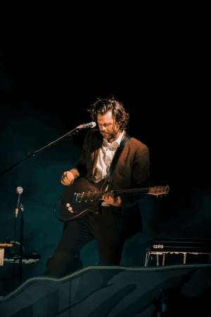Man playing guitar on stage with a microphone