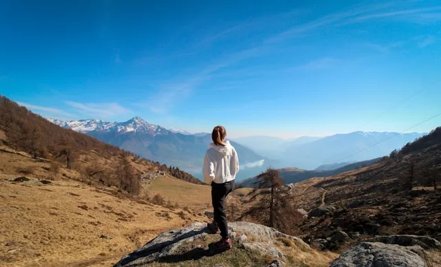 Woman overlooking a wide mountain landscape with open sky and distant peaks