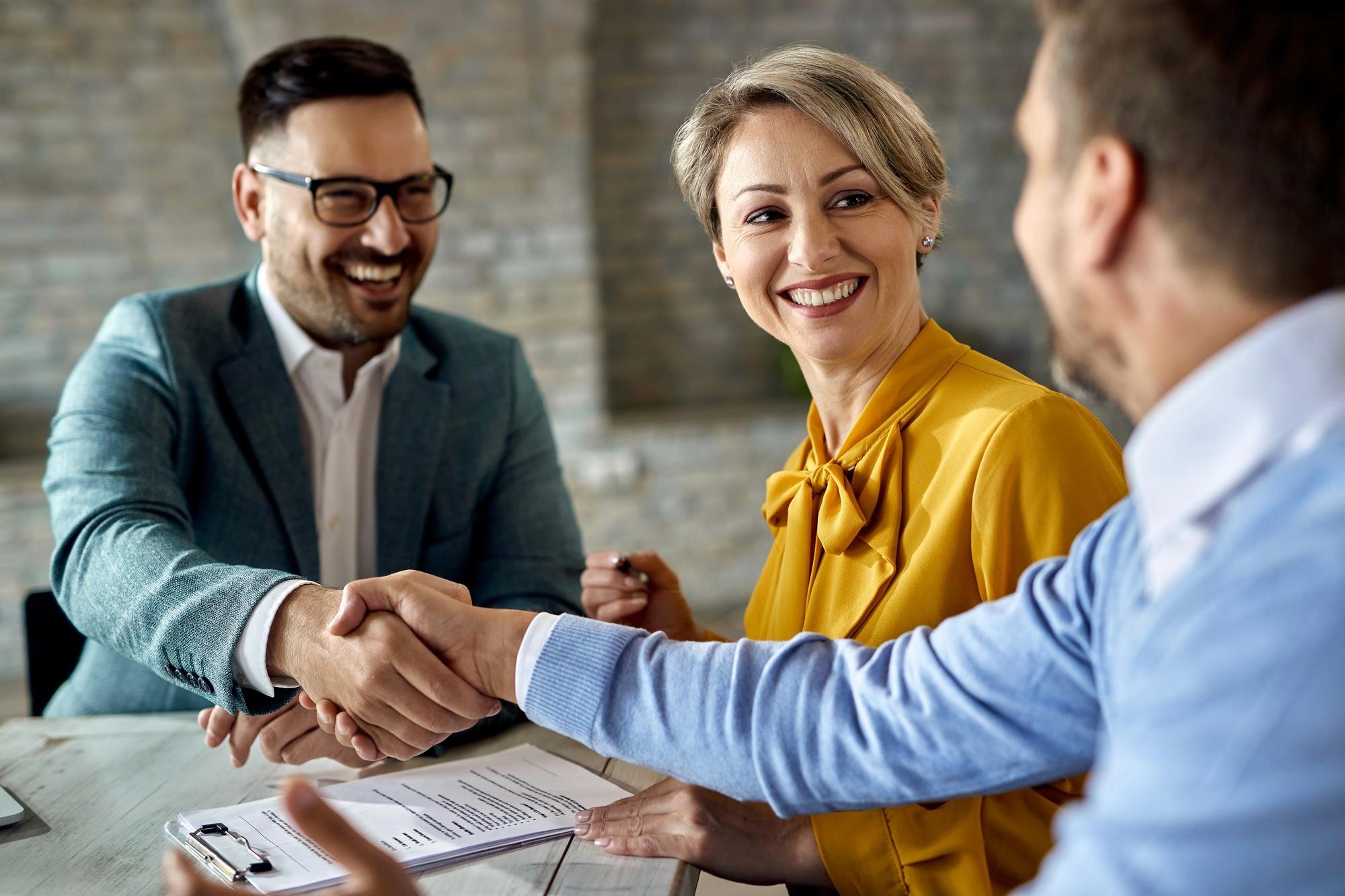 middle aged couple shaking hands with finance broker brisbane