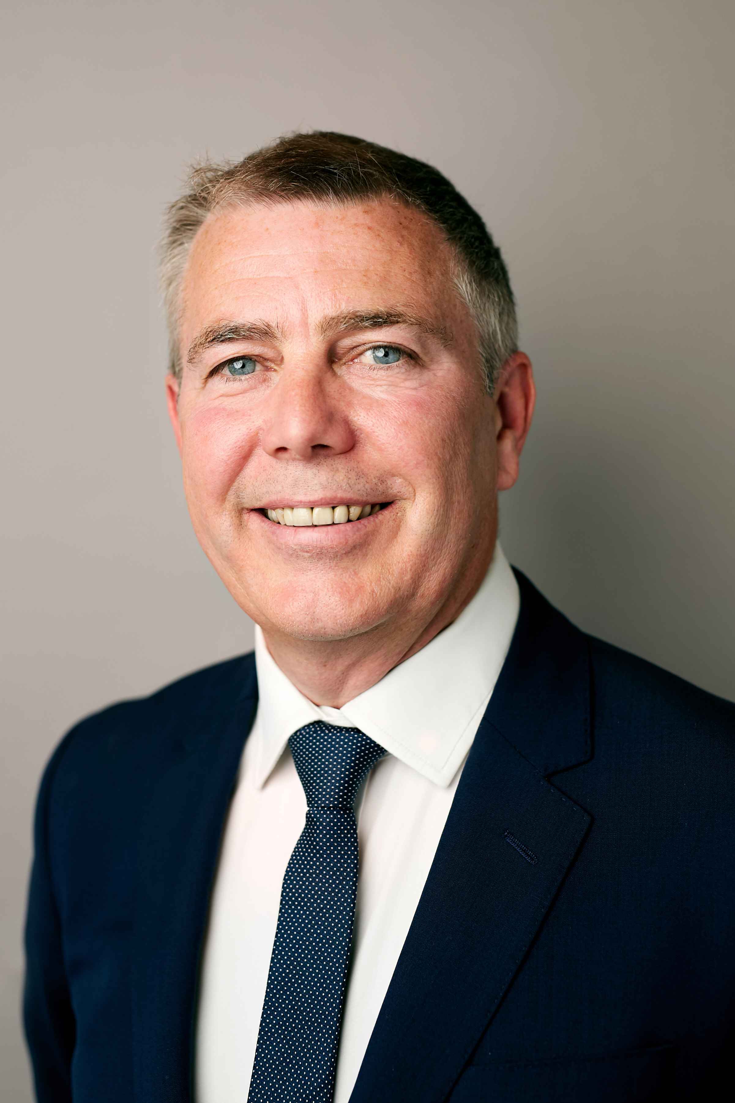 Man in dark suit, white shirt, and polka dot tie.