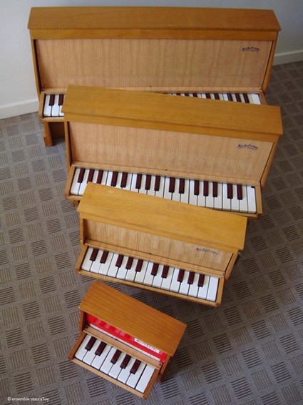 Five Michelsonne toy pianos of different sizes arranged vertically from largest to smallest.