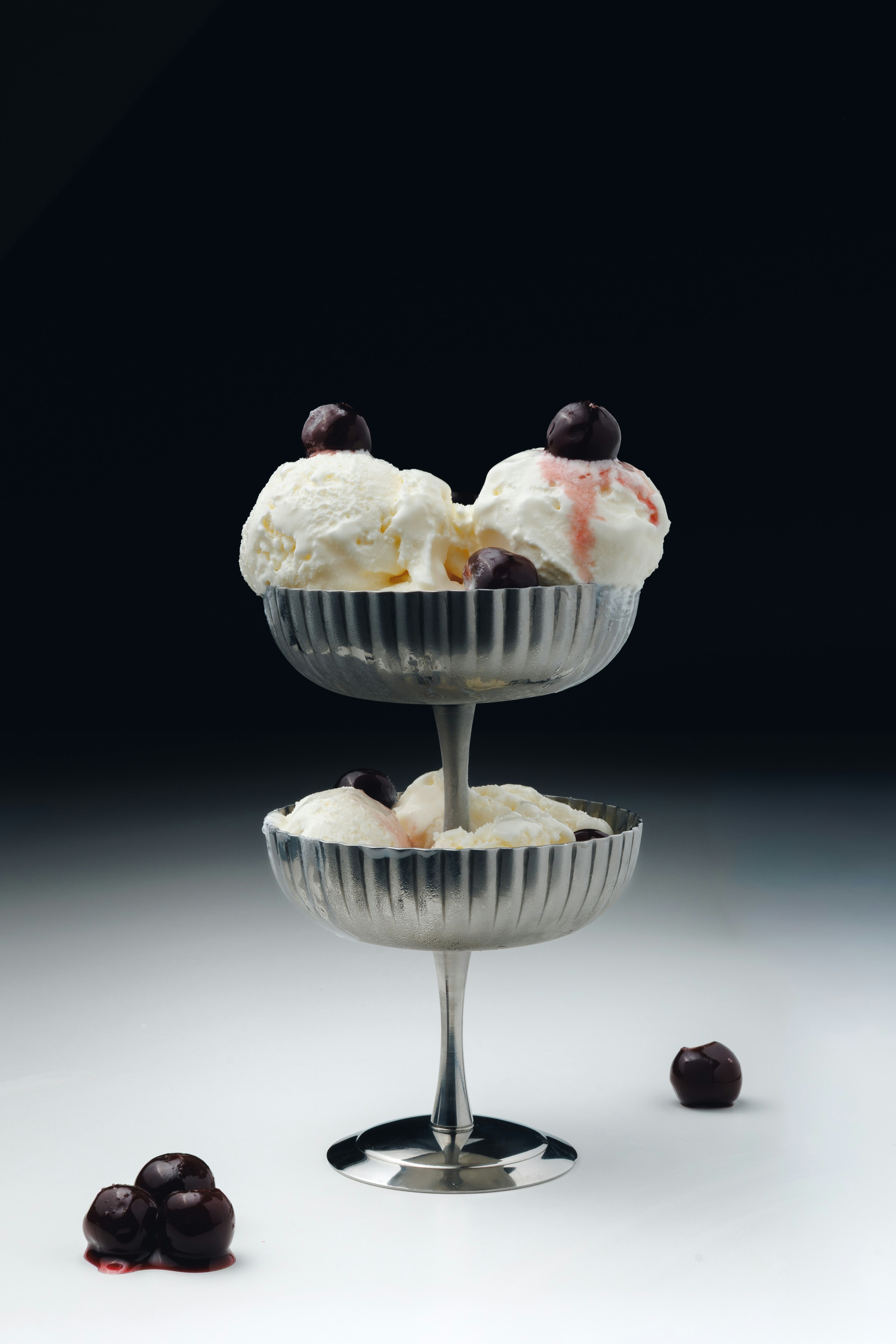 Two-tiered silver stand with vanilla ice cream and cherries