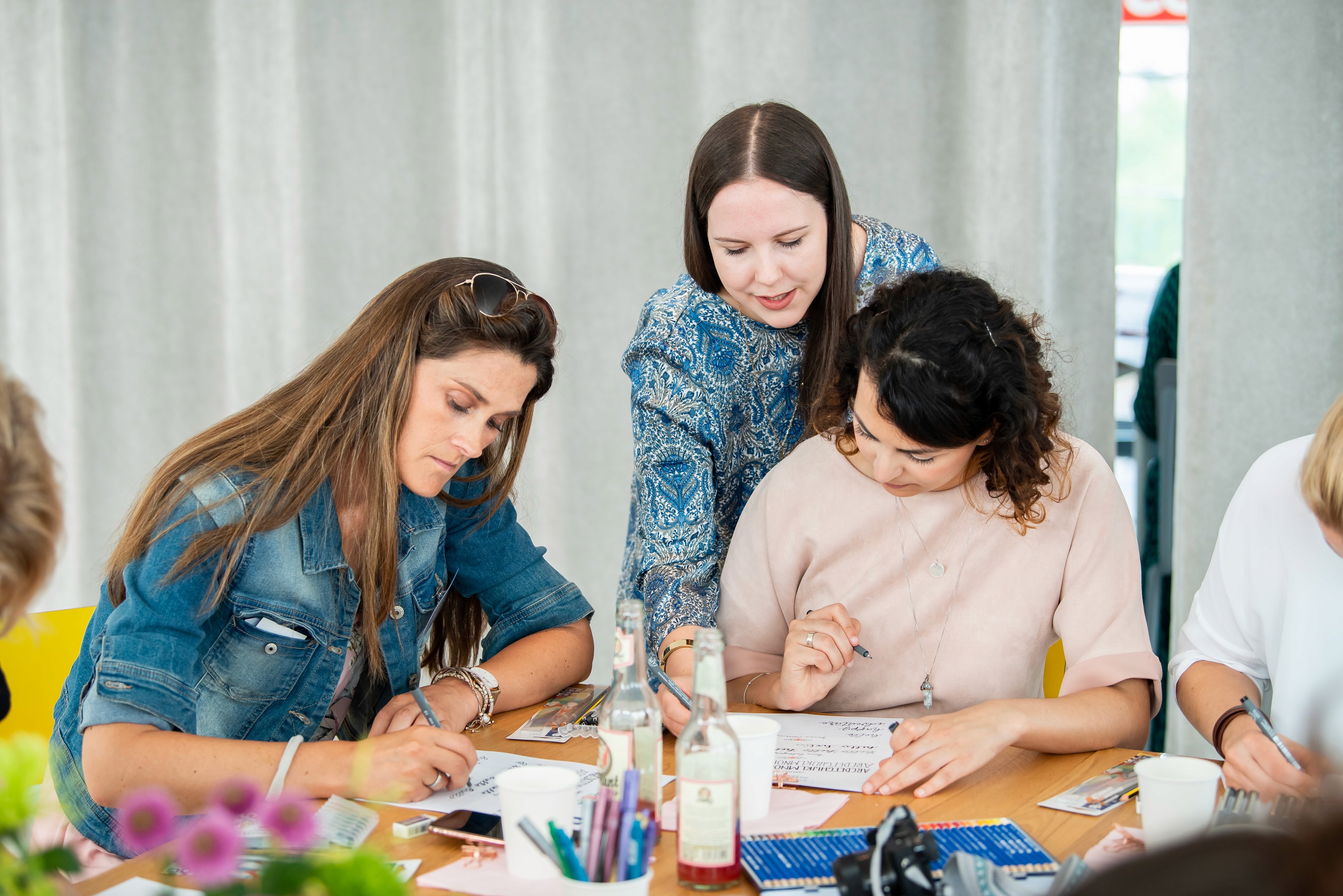 Zwei Frauen lachen während eines DIY-Workshops mit Schutzanzügen in einem Kreativzelt