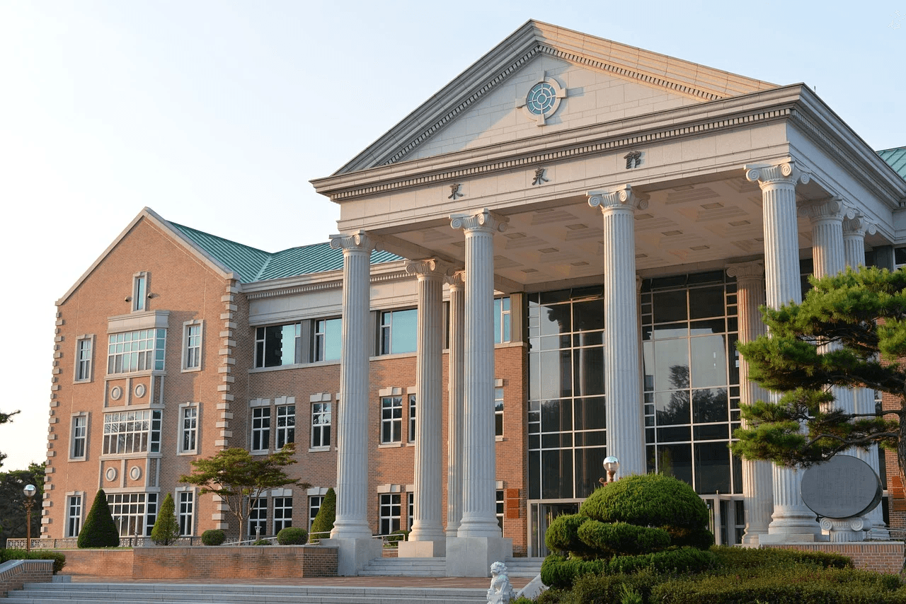 Modern neoclassical-style building with tall white columns and landscaped greenery in front.